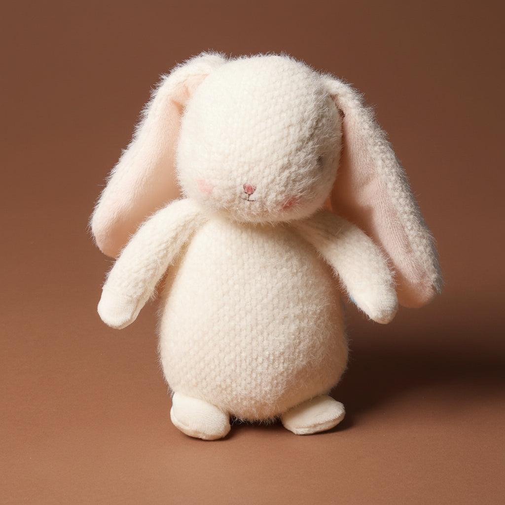 White plush petite-bun-bun-bunny toy on a brown background