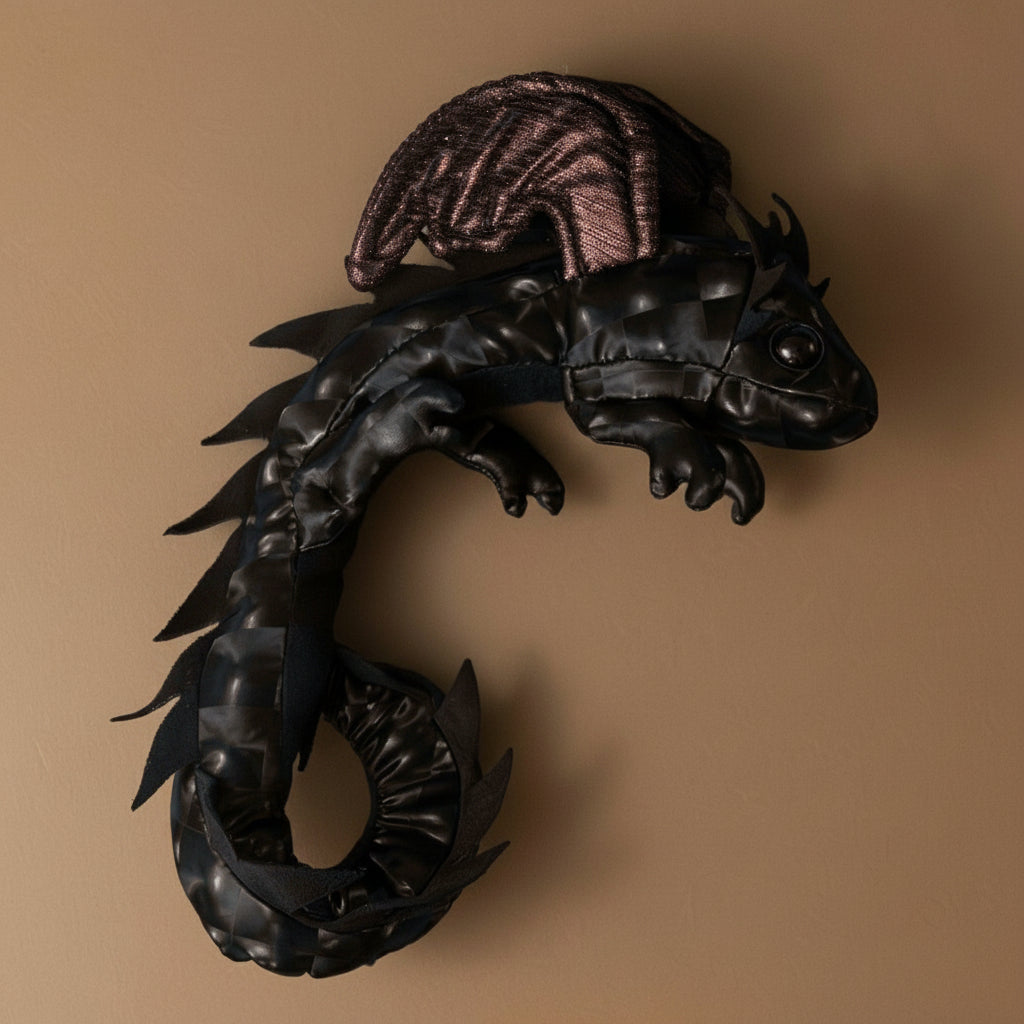 petite-dragon-wristlet-midnight Black dragon-shaped decorative item on a brown background