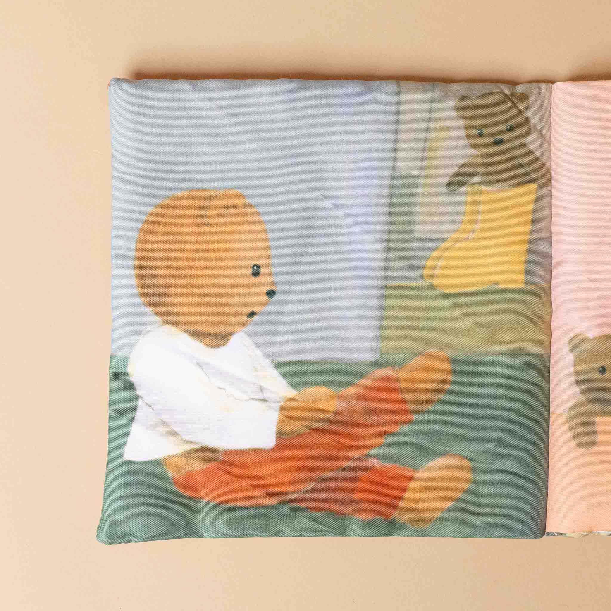 petite-fabric-book-marcel-the-bear Illustration of a teddy bear reading a book with a window view, on a beige background.