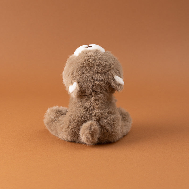 A small plush petite-gluepot-bear in brown faux fur with a white snout and ears, sitting on a solid warm brown background