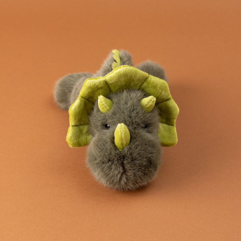 A small plush toy petite-gluepot-dino shown from the back, featuring fluffy gray-brown fur, small yellow horns, and yellow wing-like accents,