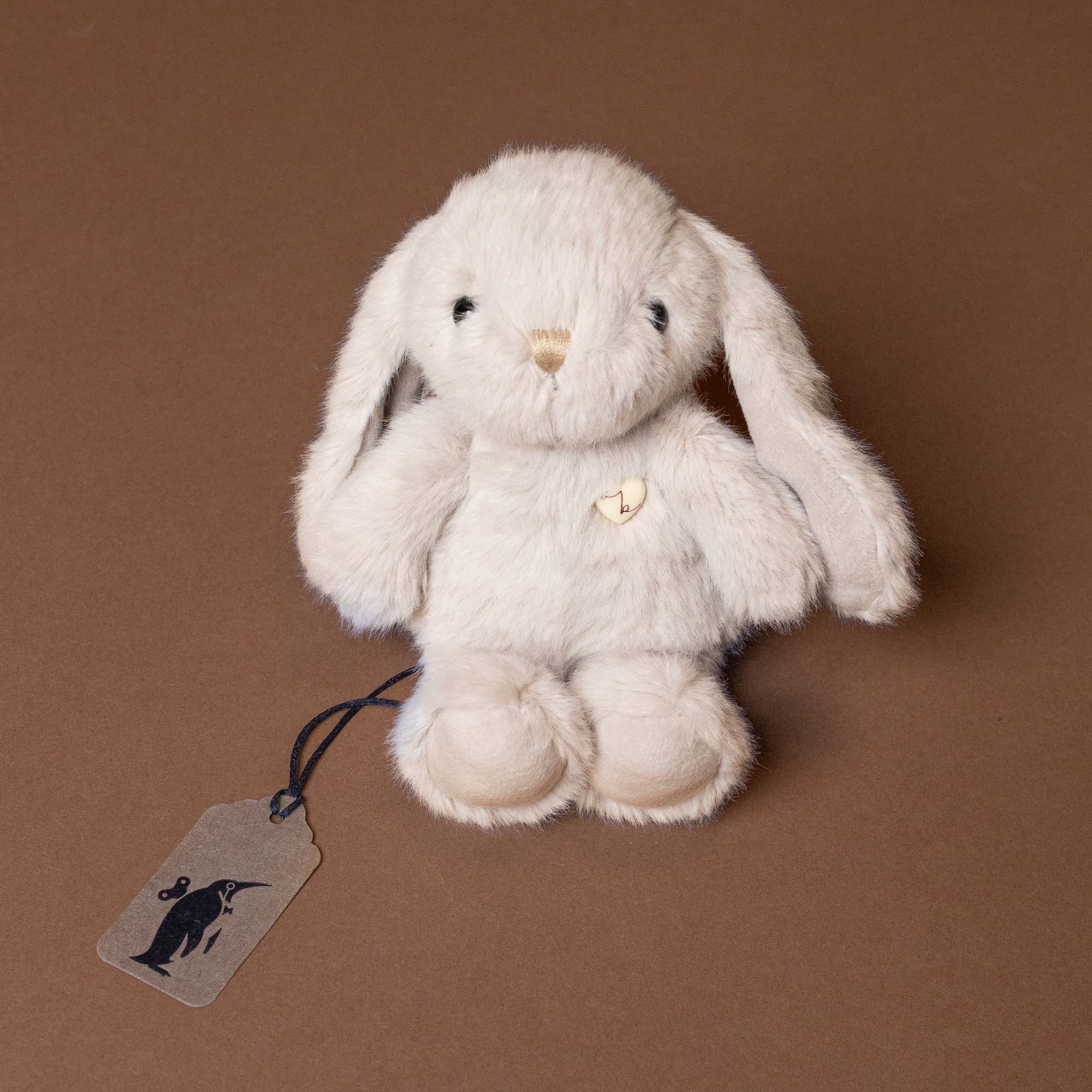 Plush bunny toy with a tag on a brown background