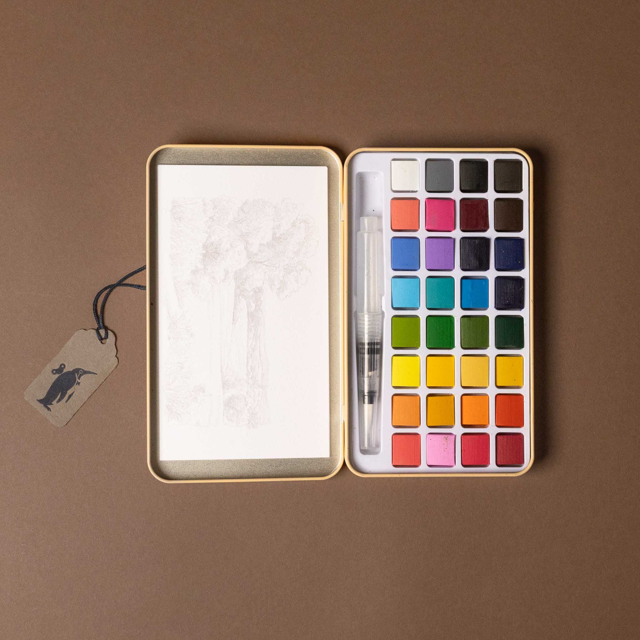 petite-watercolor-painting-kit-english-countryside Watercolor set with paint pallet, paper, and brush on a brown background