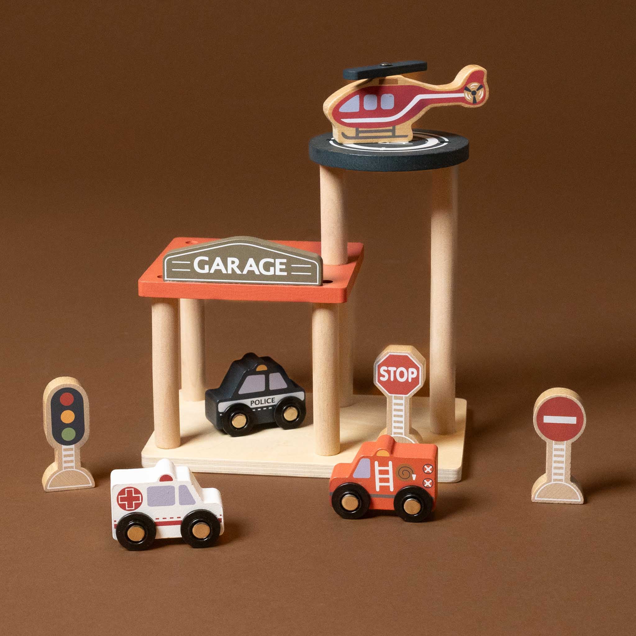 petite-wooden-garage-with-cars Wooden toy set with a garage, helicopter, cars, and traffic lights on a brown background