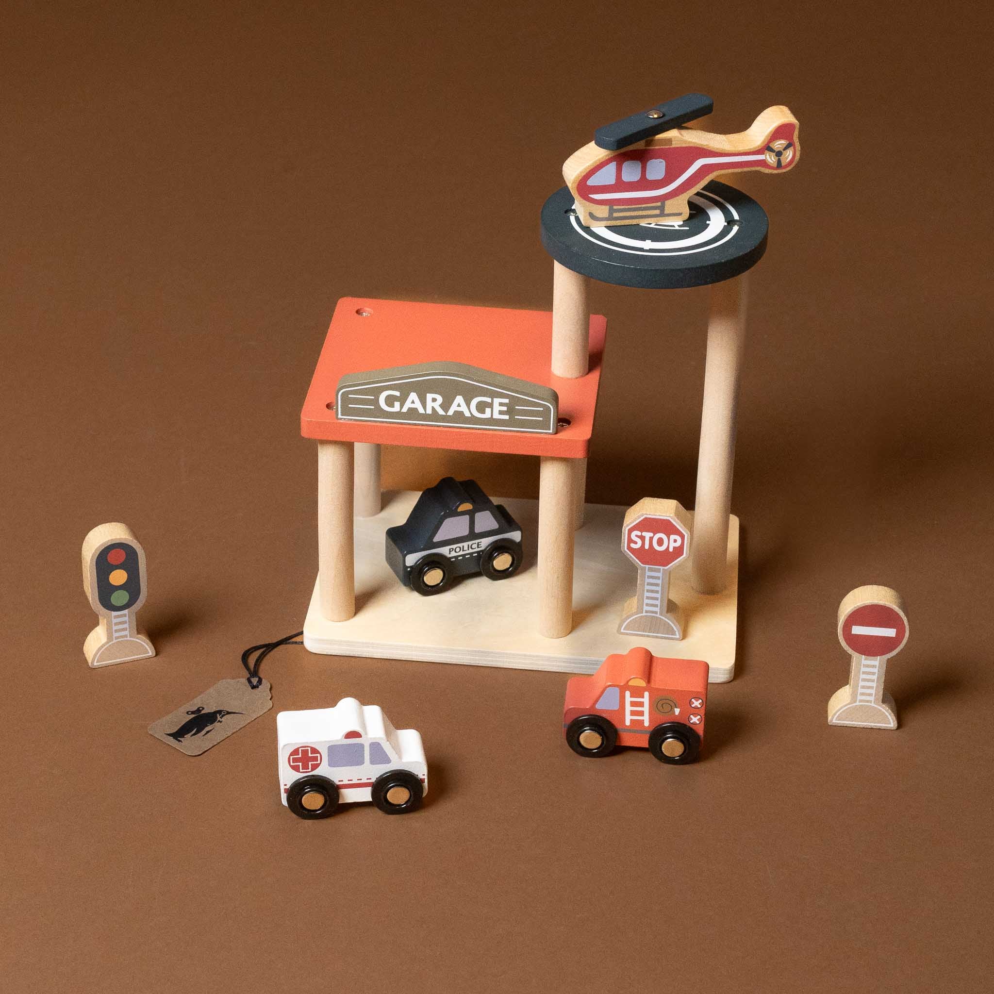 petite-wooden-garage-with-cars Wooden toy set with a garage, helicopter, cars, and traffic lights on a brown background