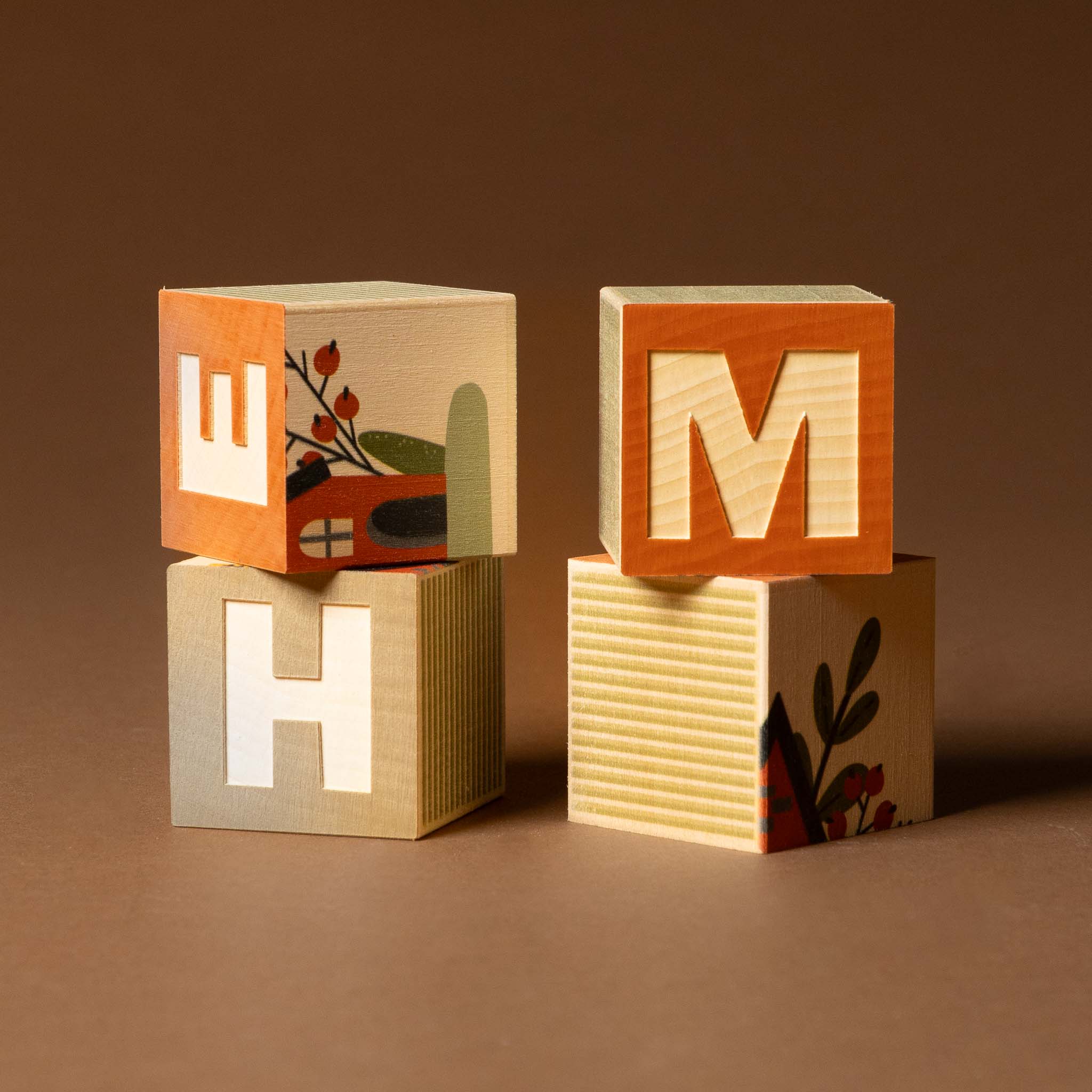 petite-wooden-gifting-block-set-home Wooden blocks with letters 'M', 'H', and 'W' on a brown background