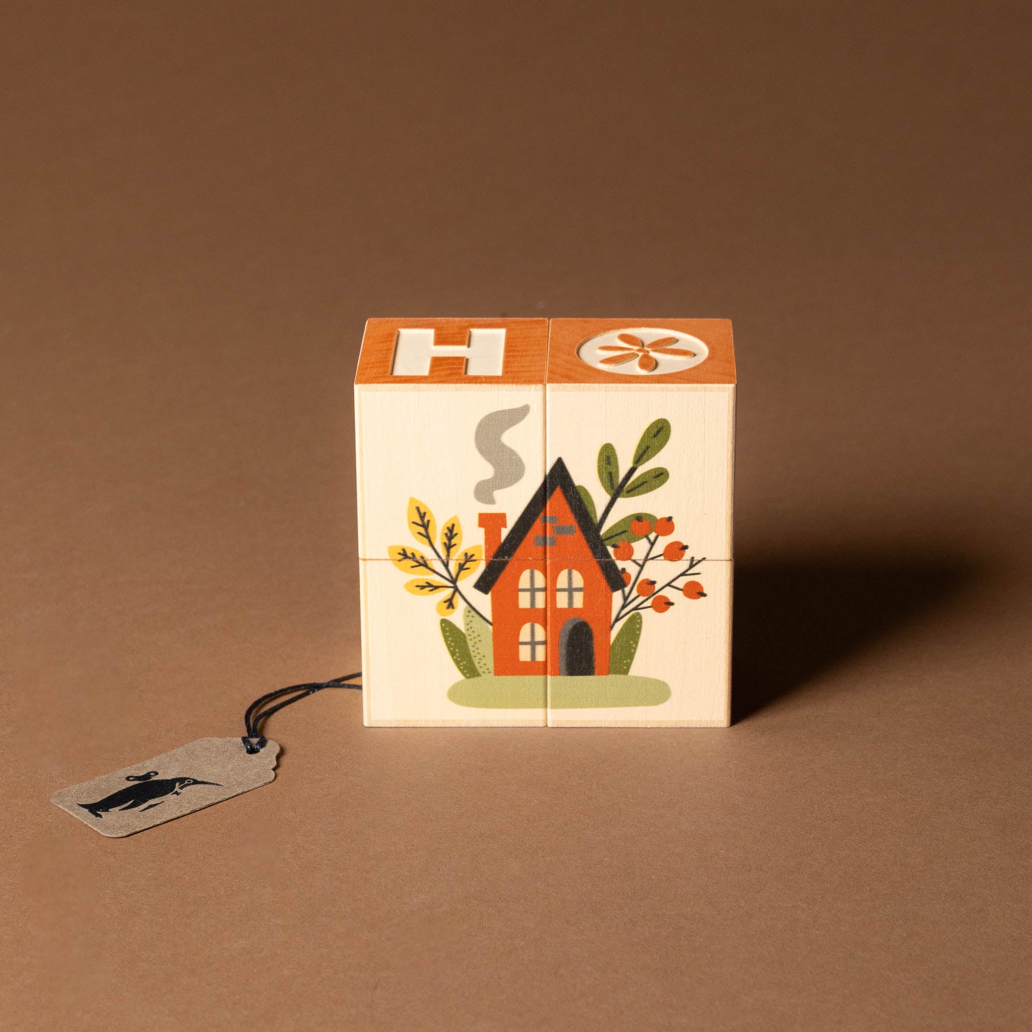 petite-wooden-gifting-block-set-home Wooden block with house illustration and tag on a brown background
