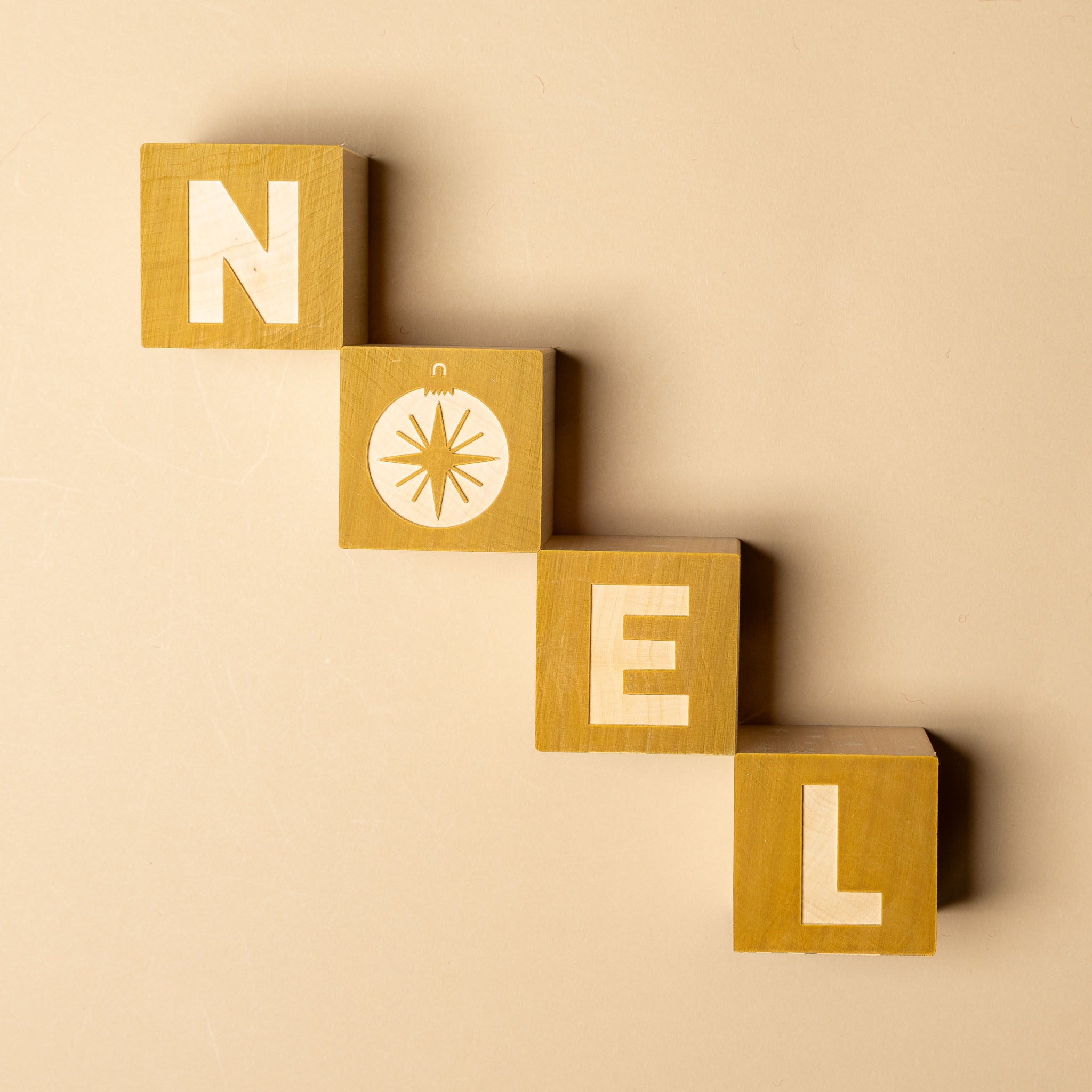 petite-wooden-gifting-block-set-snowglobe Wooden blocks spelling 'NOEL' on a beige background