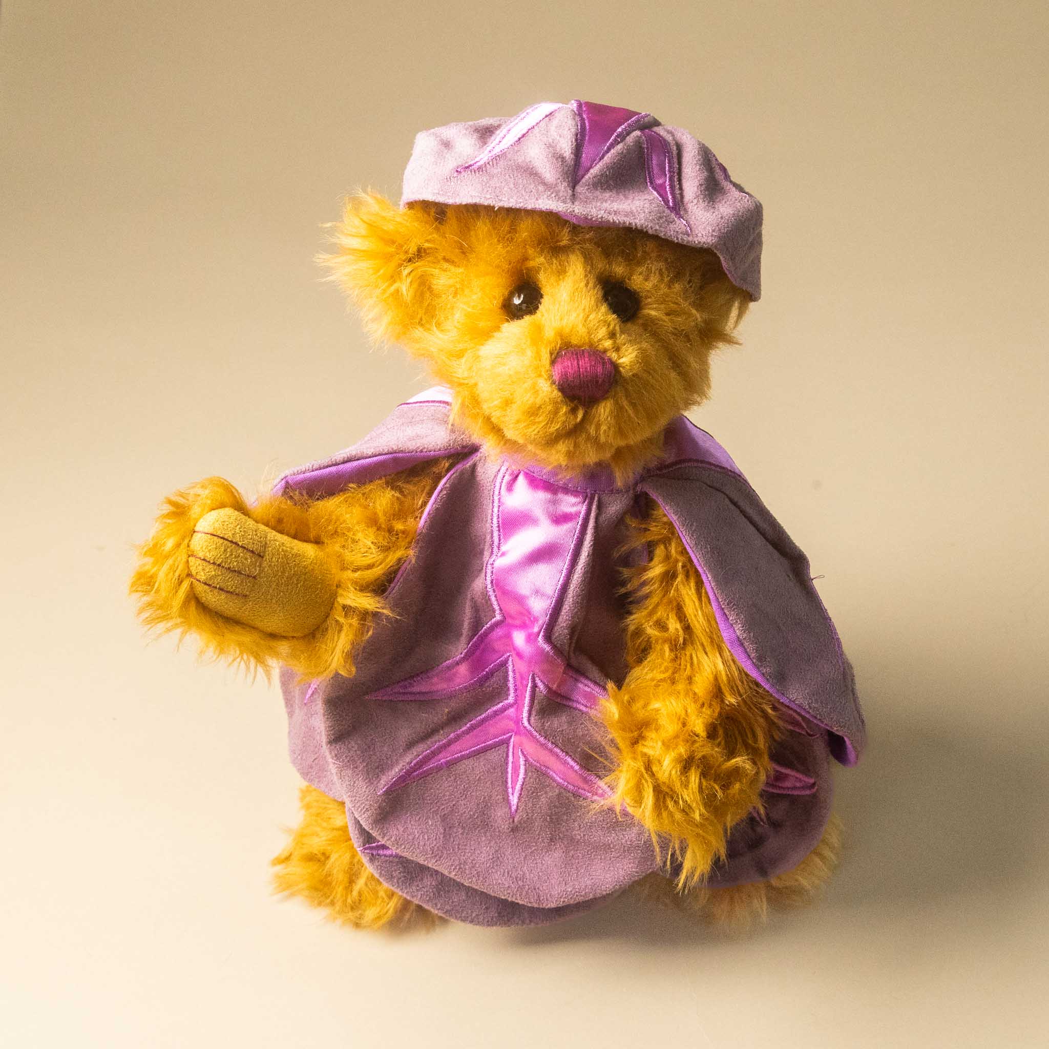 pickles-the-red-cabbage-bear in a purple outfit with a matching hat on a beige background