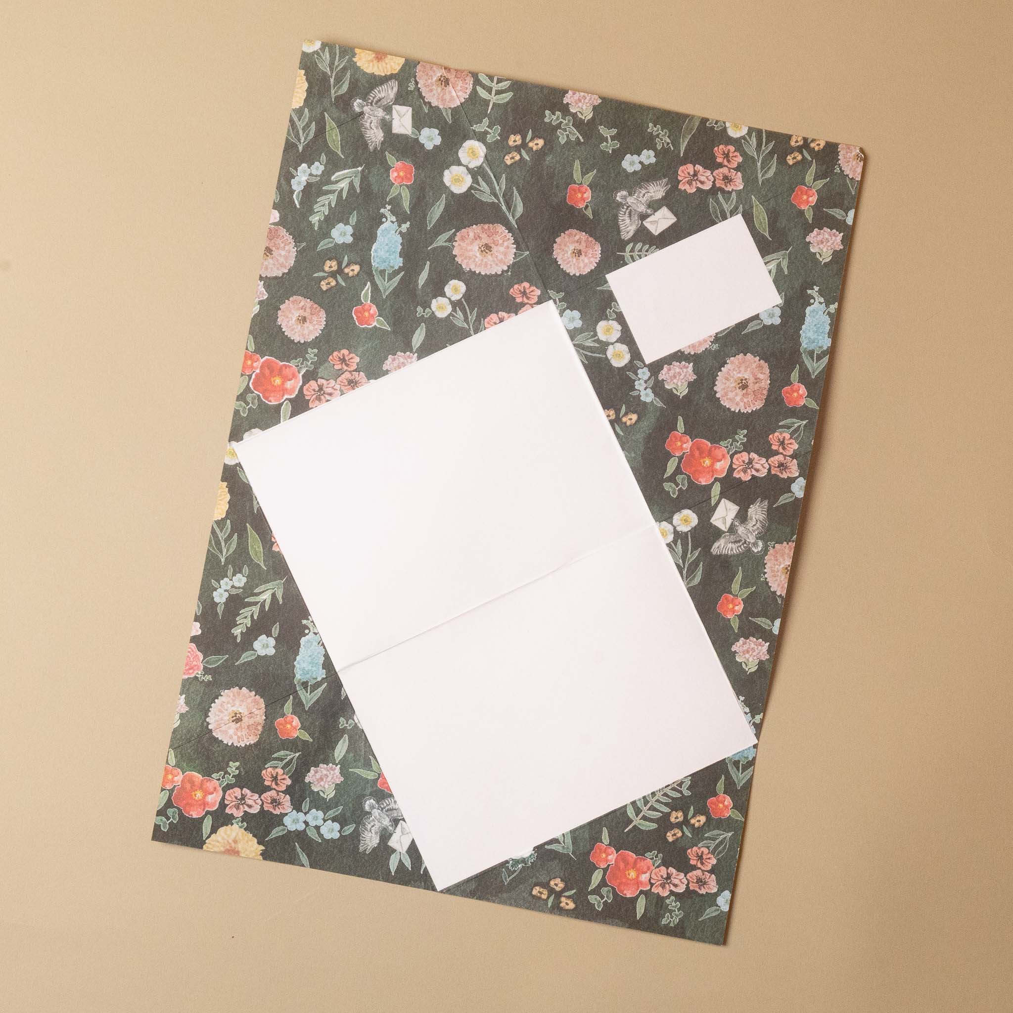 A floral-patterned envelope with a white insert card, photographed from above on a plain beige background.