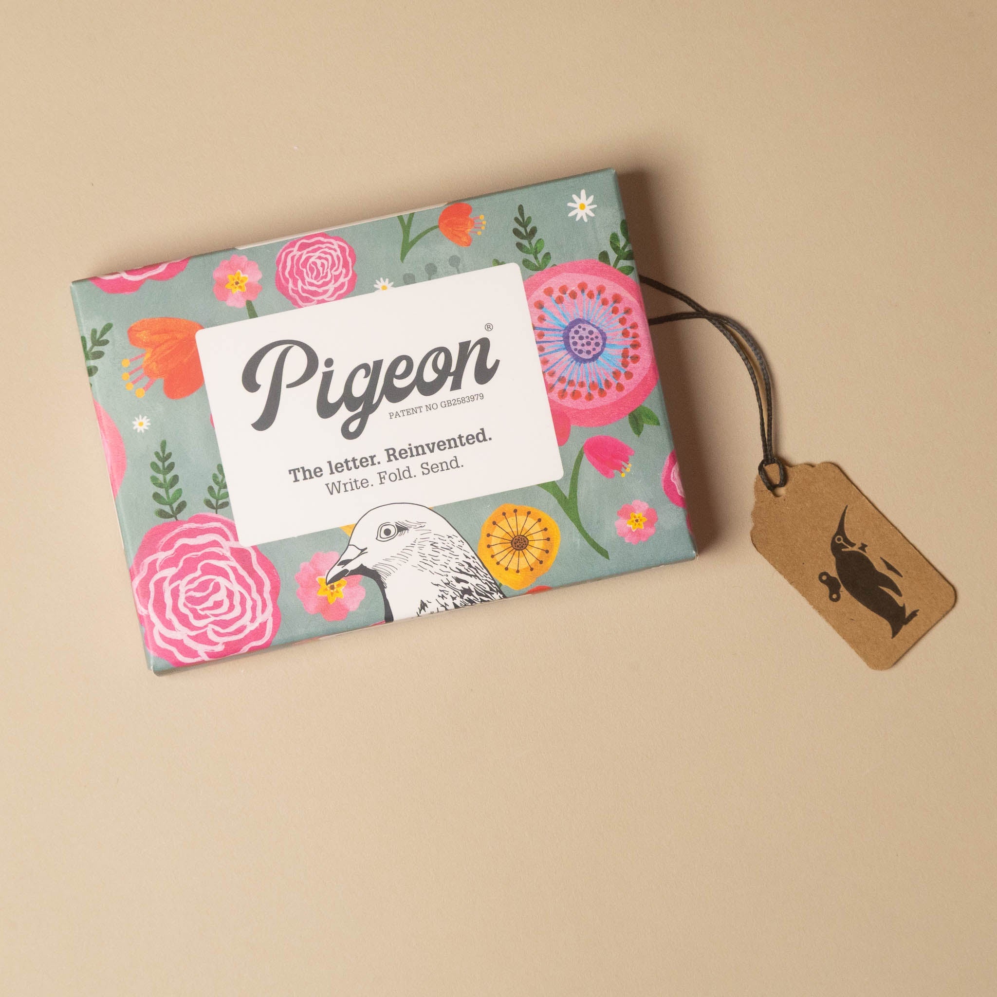 A Pigeon letter packaging box with a floral pattern on a beige background, featuring a brown paper hangtag with a black silhouette logo.