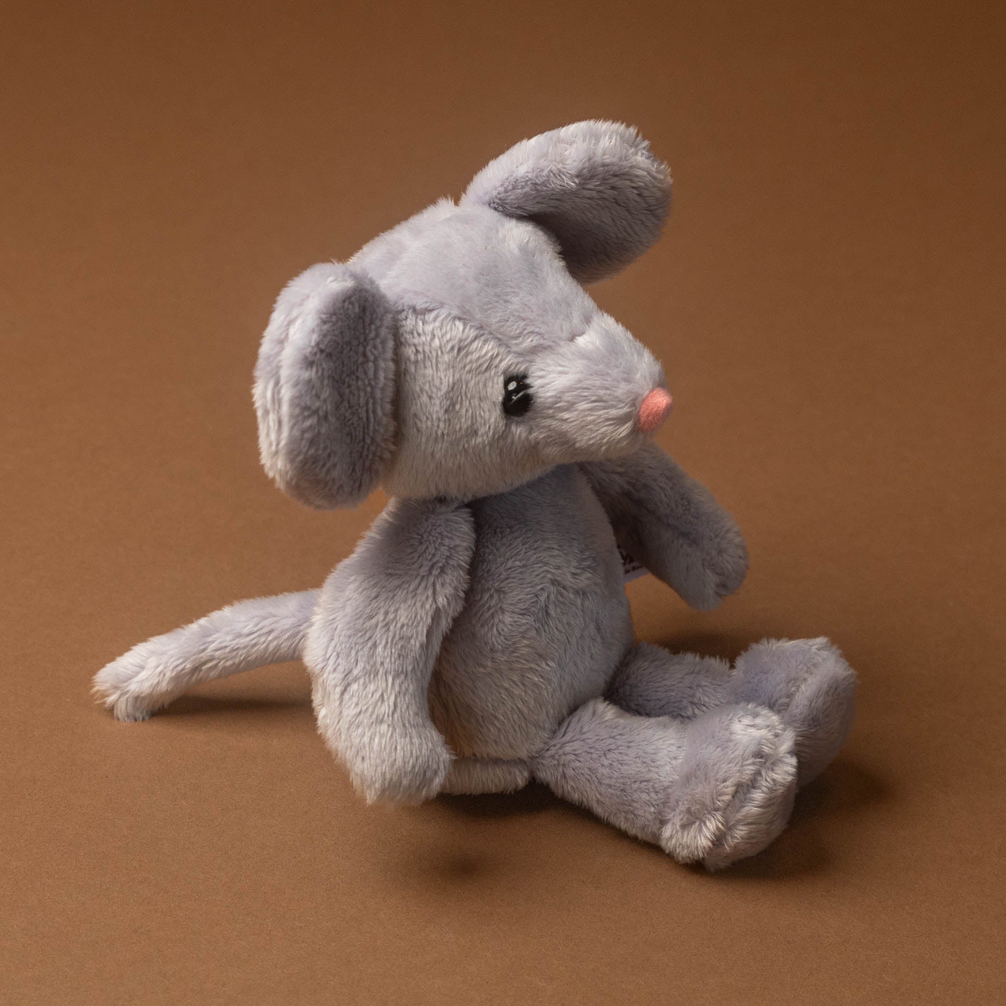 Gray plush pip-the-mouse toy on a brown background