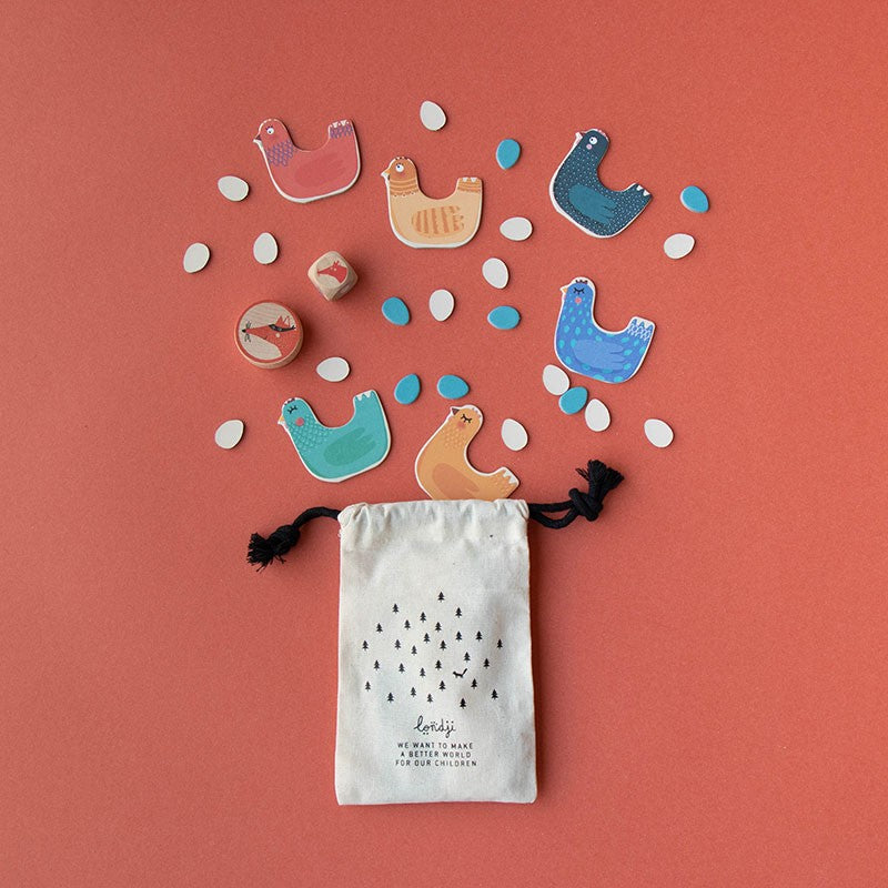 pocket-game-cluck-cluck-the-fox Colorful bird-shaped game pieces with a drawstring bag on a red background
