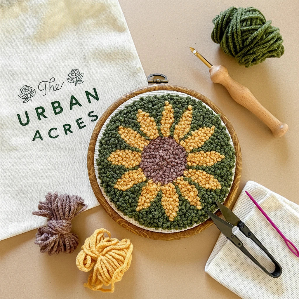 Embroidery hoop with sunflower design, yarn, and tools on a white background, featuring The Urban Acres brand.