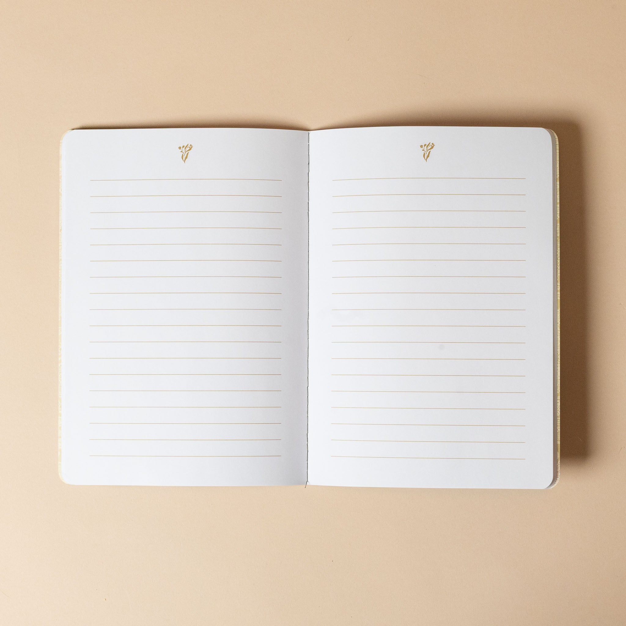 reverie-floral-notebook-hibiscus-co Open notebook with lined pages on a beige background