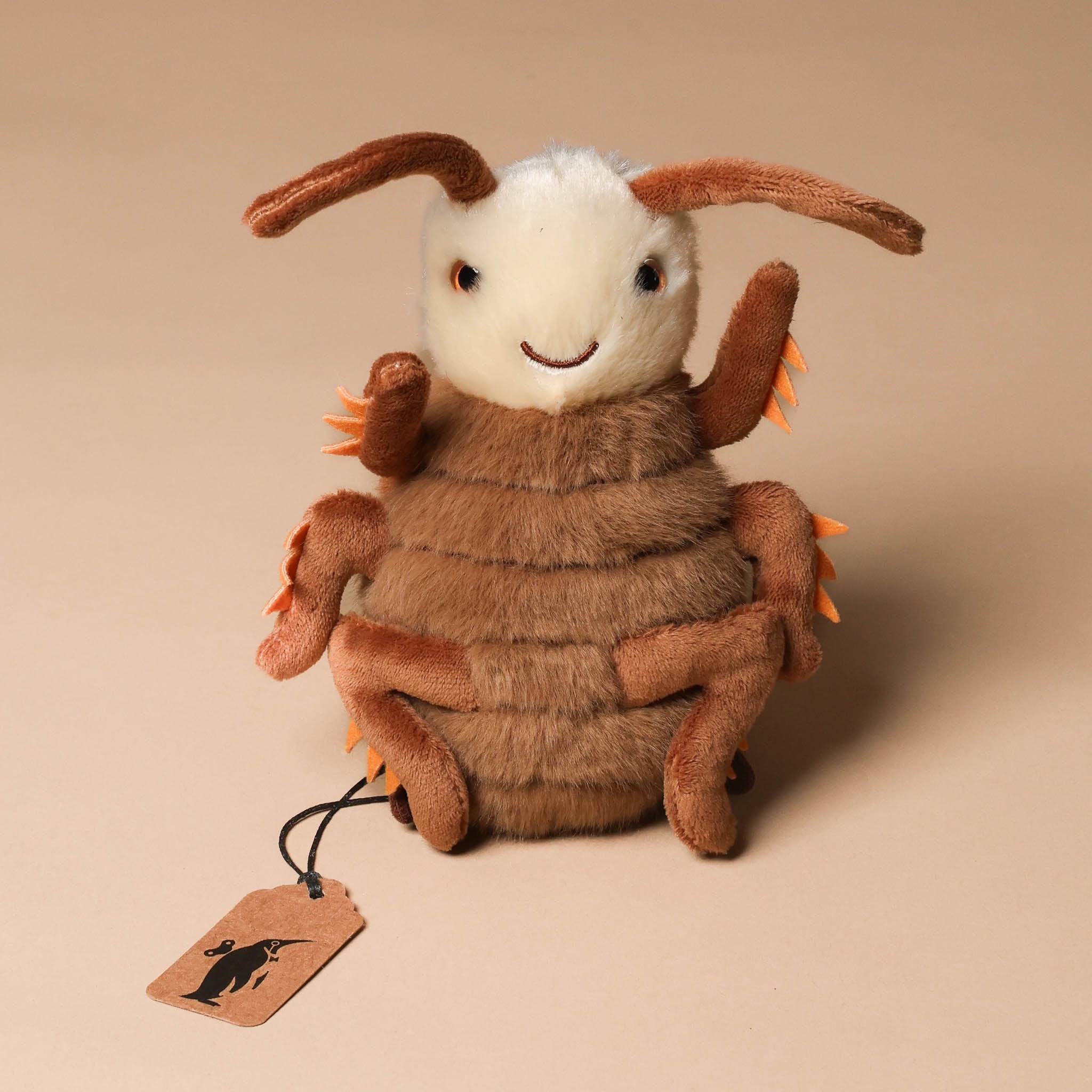 Plush toy rrocco-the-cockroach with brown fur and white face on a beige background