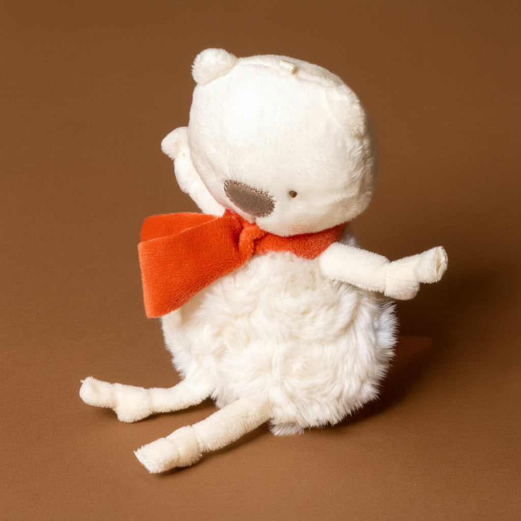 White plush roly-poly-polar-bear- ith a red bow tie on a brown background