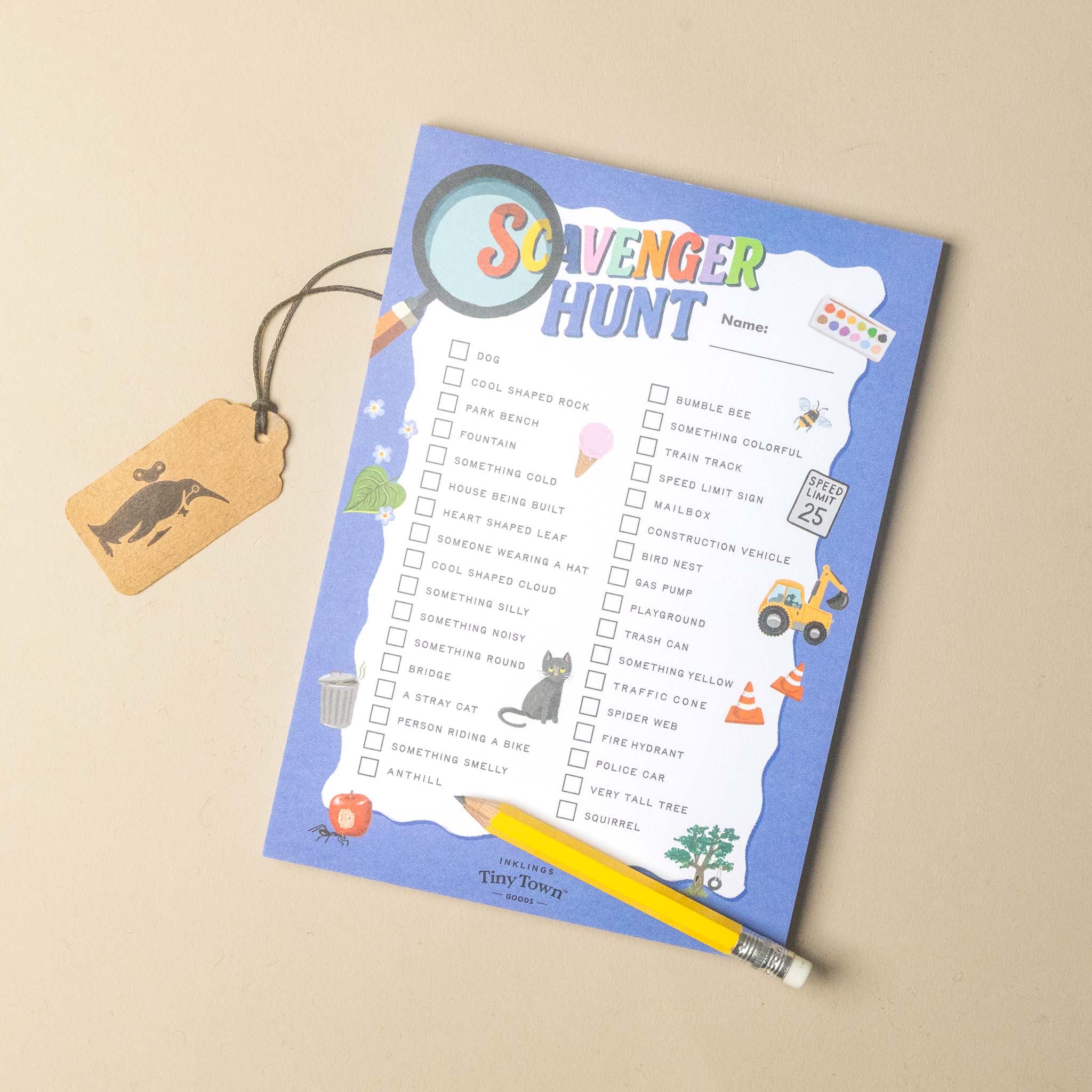 A children's 'Scavenger Hunt' activity sheet with a blue border, a checklist on a white background, a small hanging tag, and a yellow pencil, photographed on a light beige surface.