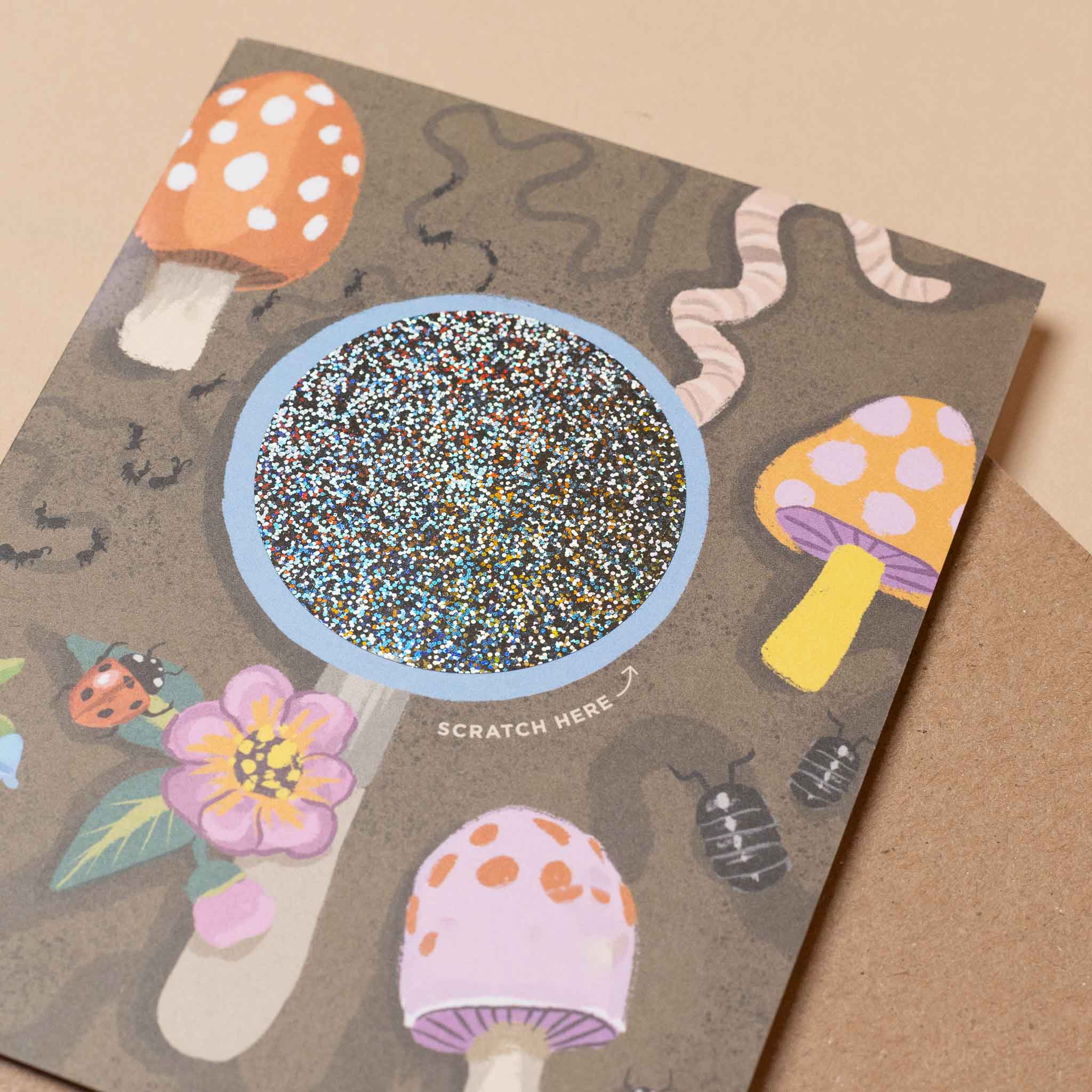 scratch-off-worm-birthday-wishes-greeting-card with mushrooms, flowers, and a bowl of sprinkles on a brown background