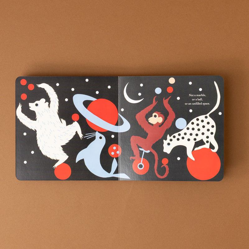 A children's picture book shown open on a warm brown background. The cover features whimsical animal illustrations on a dark space-themed background, including a white polar bear, a blue seal, a red monkey on a unicycle, and a white-and-black spotted cat, with small printed text on the right page.