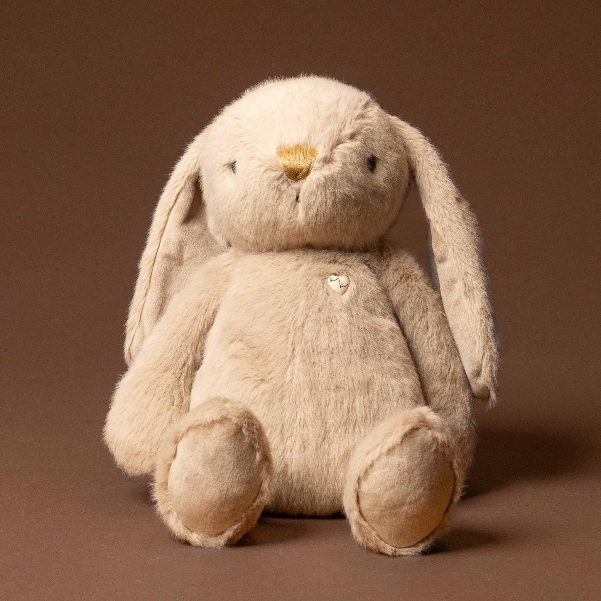 Plush snuggle-bunny-caramel toy on a brown background