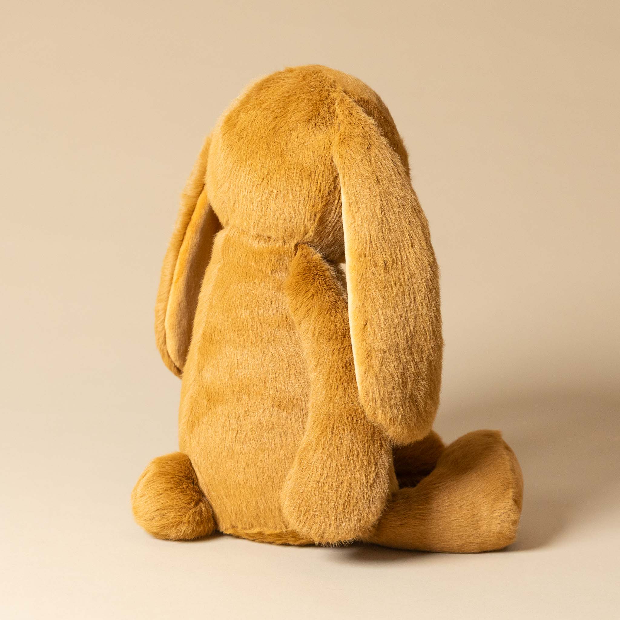 Brown plush snuggle-bunny-toffee toy on a beige background