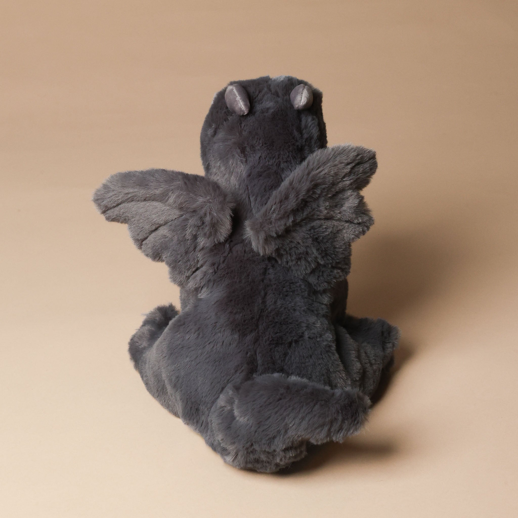 Plush sootie-the-dragon toy on a beige background