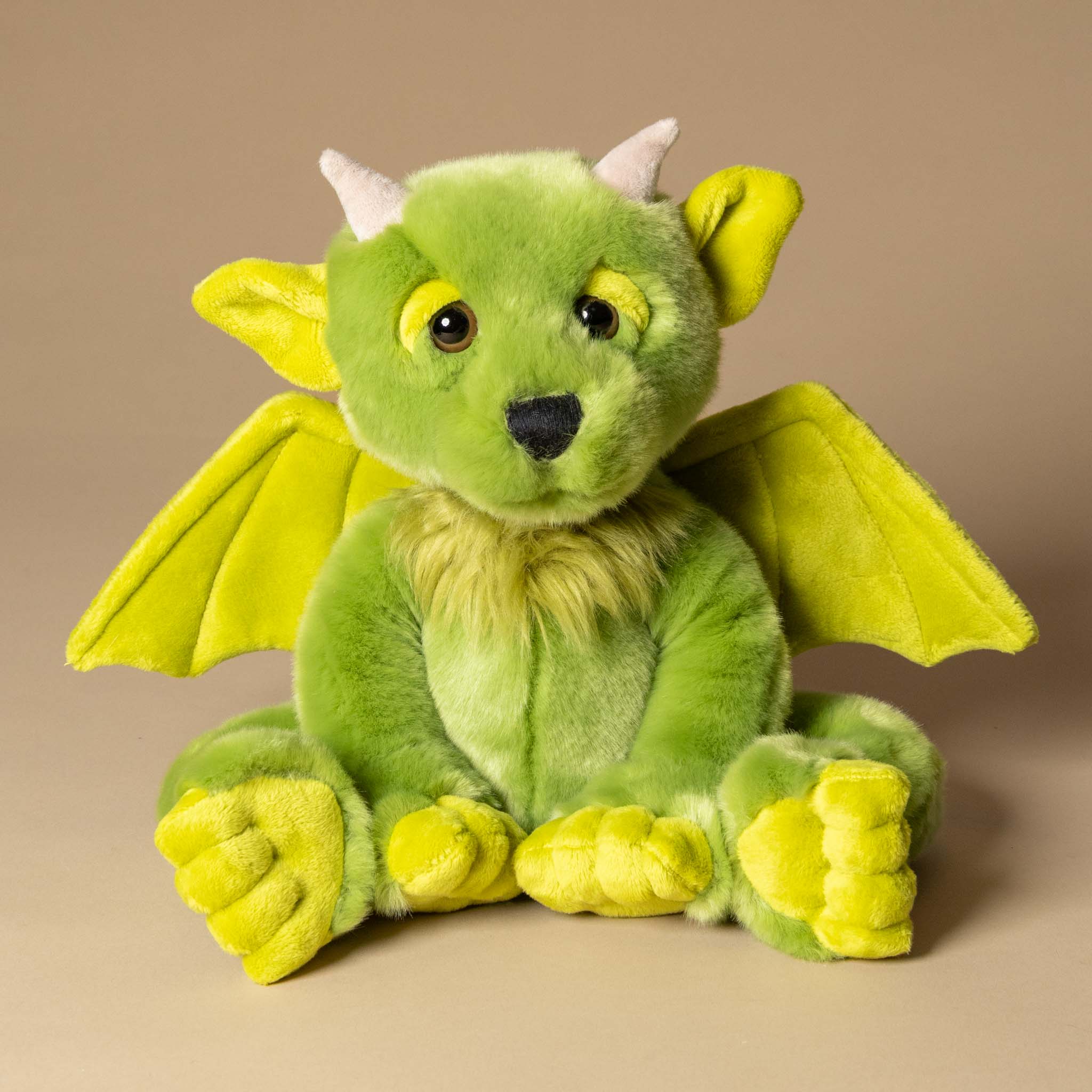 spires-the-forest-gargoyle Green plush dragon toy with yellow accents on a beige background