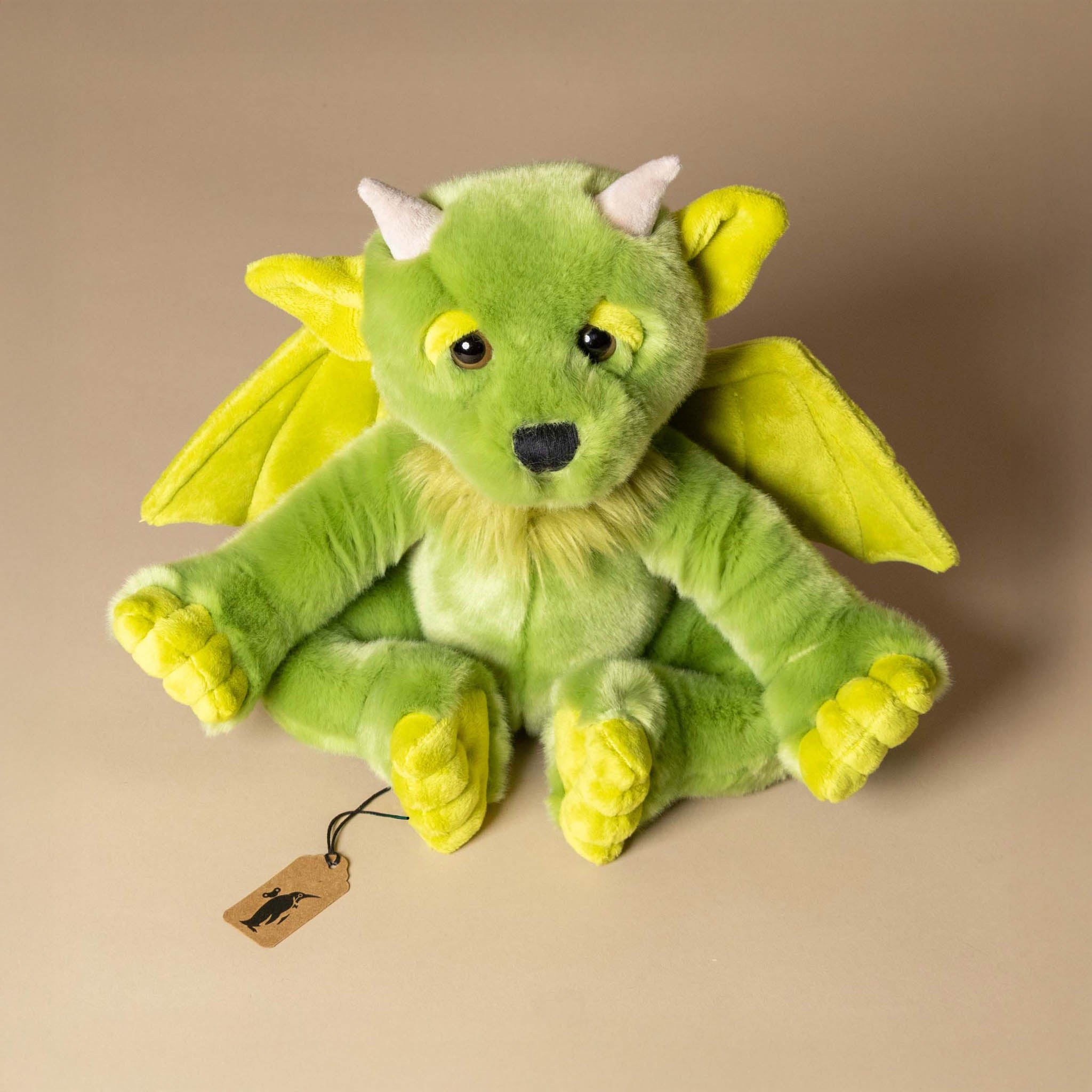 spires-the-forest-gargoyle Green plush dragon toy with yellow accents on a beige background