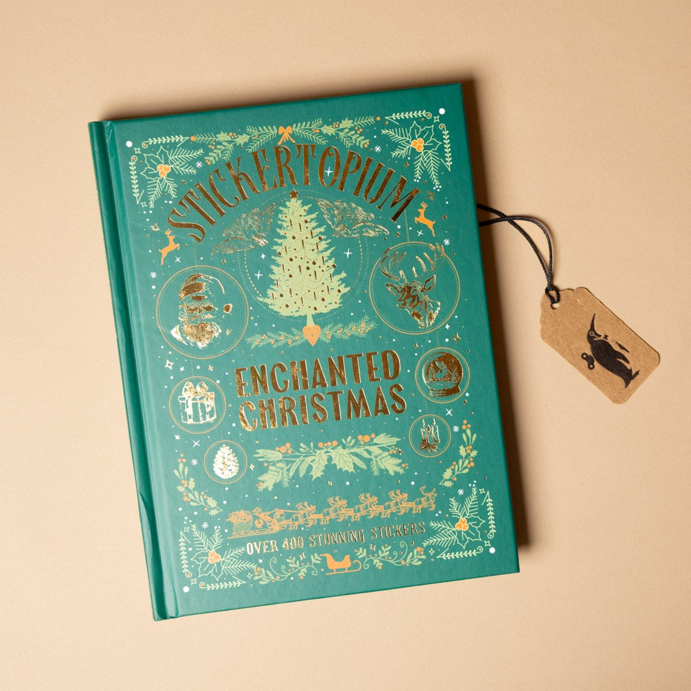 Teal book titled 'Stickertopium Enchanted Christmas' with decorative elements on a beige background