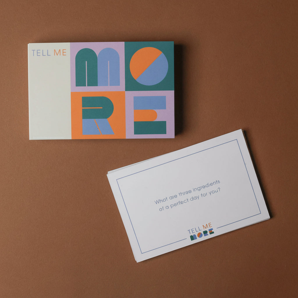 Colorful card with 'Tell Me More' design on a brown background