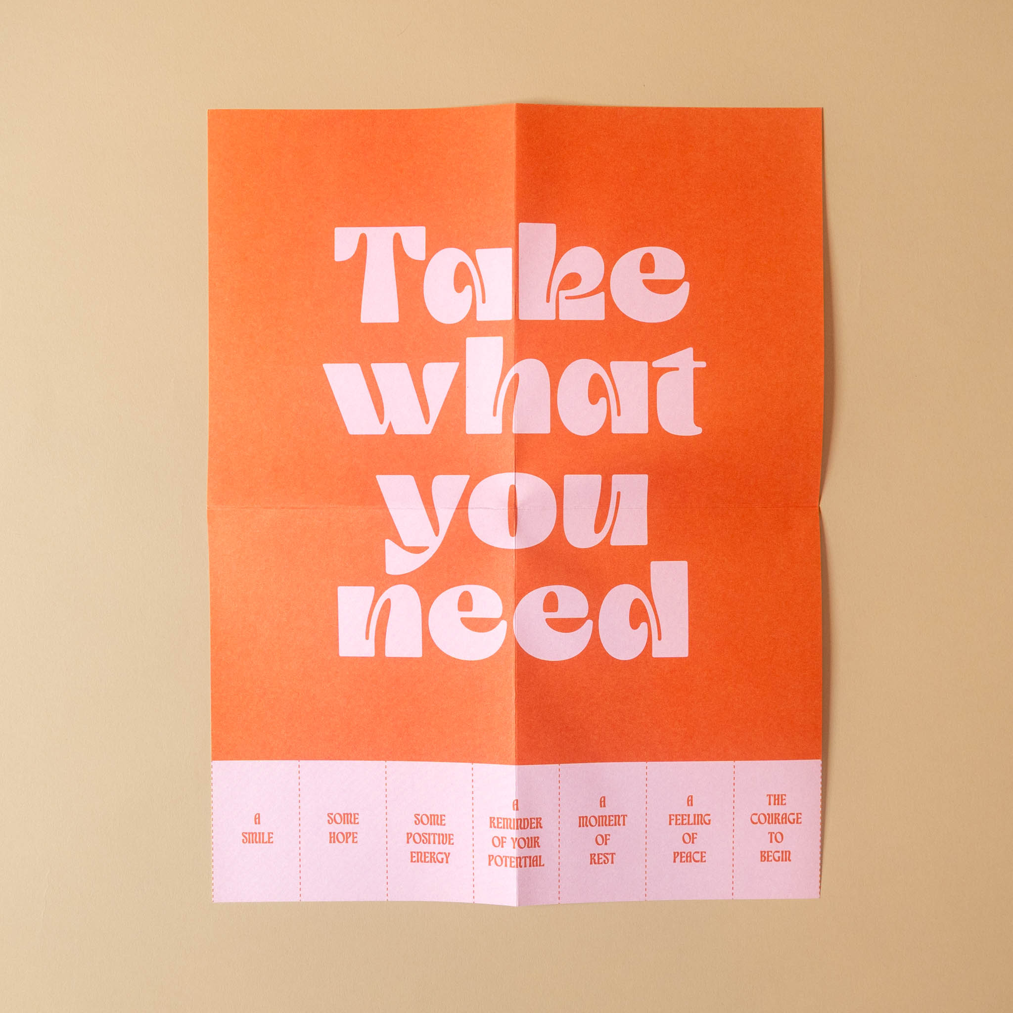 An red paper poster with large white text reading 'Take what you need' centered on a beige background. The bottom margin includes small pink and red text sections.