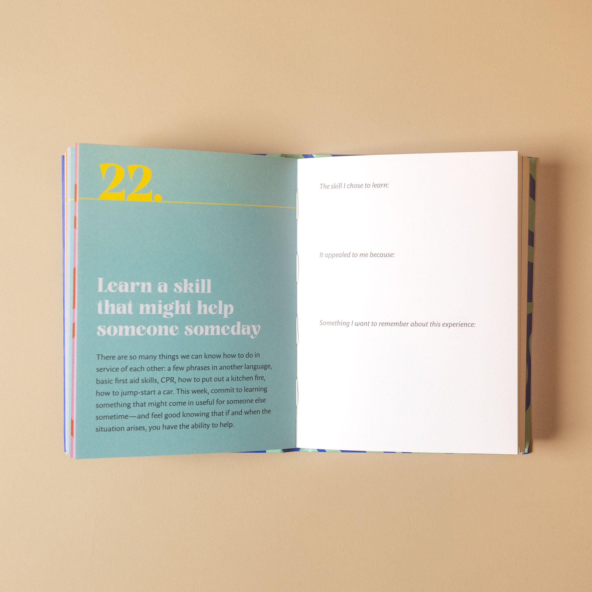 An open booklet or journal page spread on a warm beige background. The left page has a light blue-green background with the yellow number 22 and the title 'Learn a skill that might help someone someday.