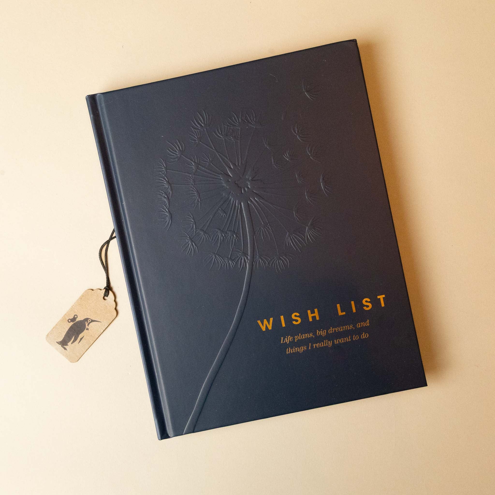 Black notebook titled 'Wish List' with a dandelion design on a beige background