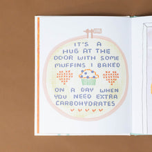 Load image into Gallery viewer, its-a-hug-at-the-door-with-some-muffins-i-baked-on-a-day-when-you-need-extra-carbohydrates-shown-as-a-sampler-cross-stitch
