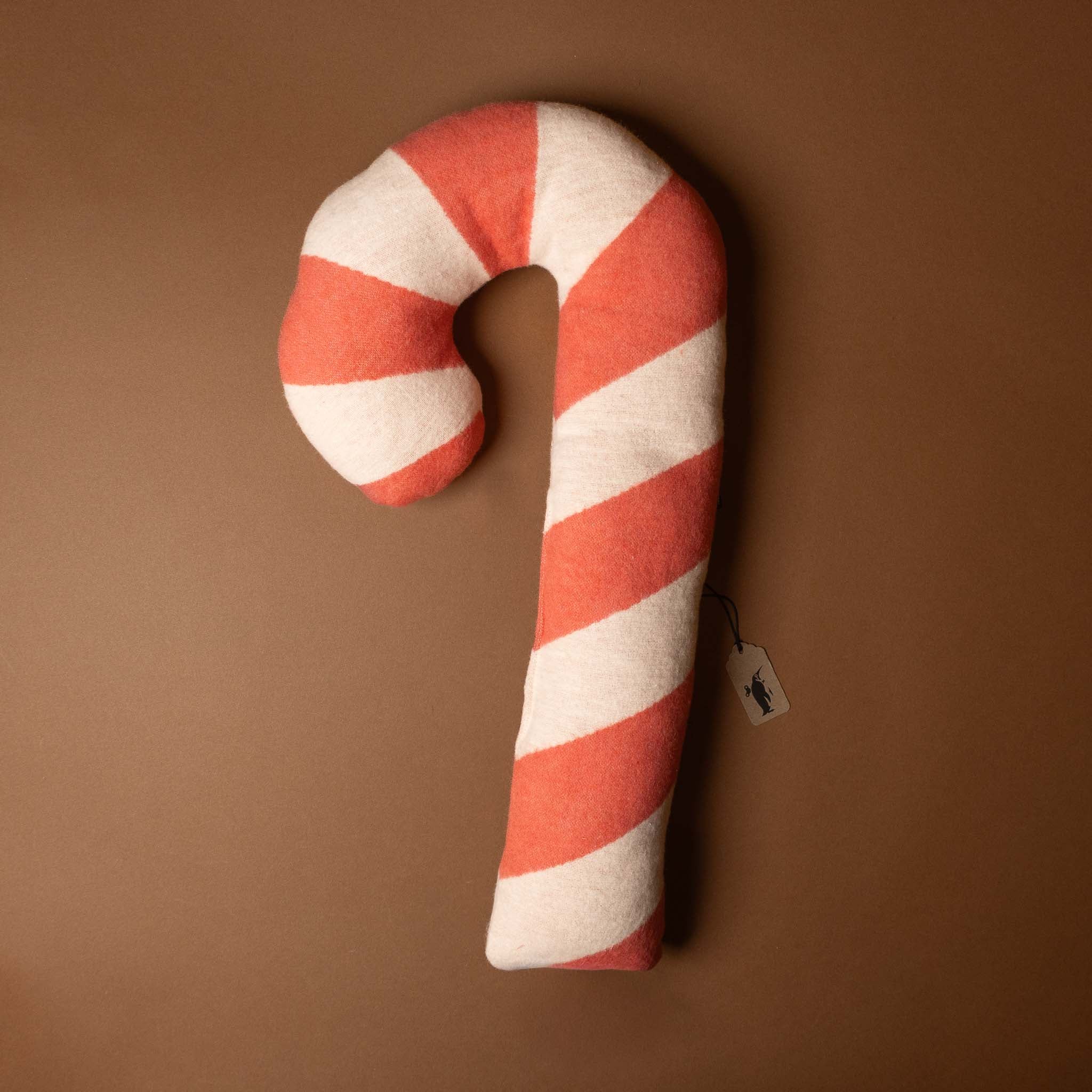 upcycled-cotton-candy-cane-cushion Candy cane-shaped pillow with red and white stripes on a brown background