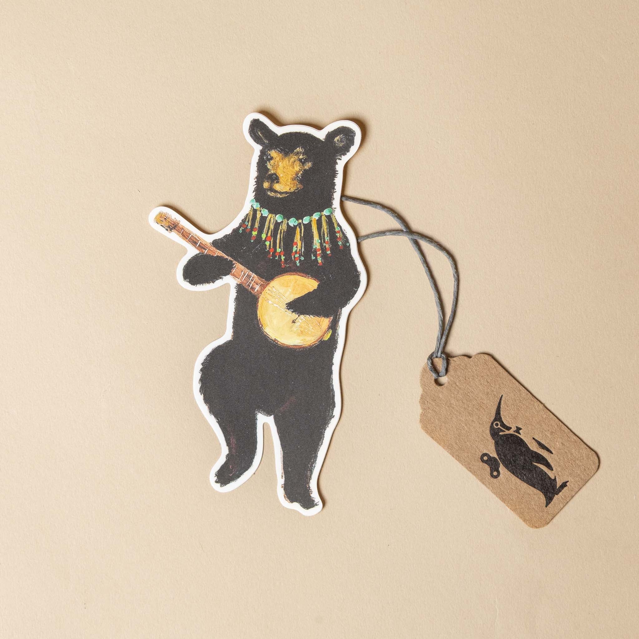 vinyl-die-cut-sticker-banjo-bear -Sticker of a bear playing a banjo with a tag on a beige background