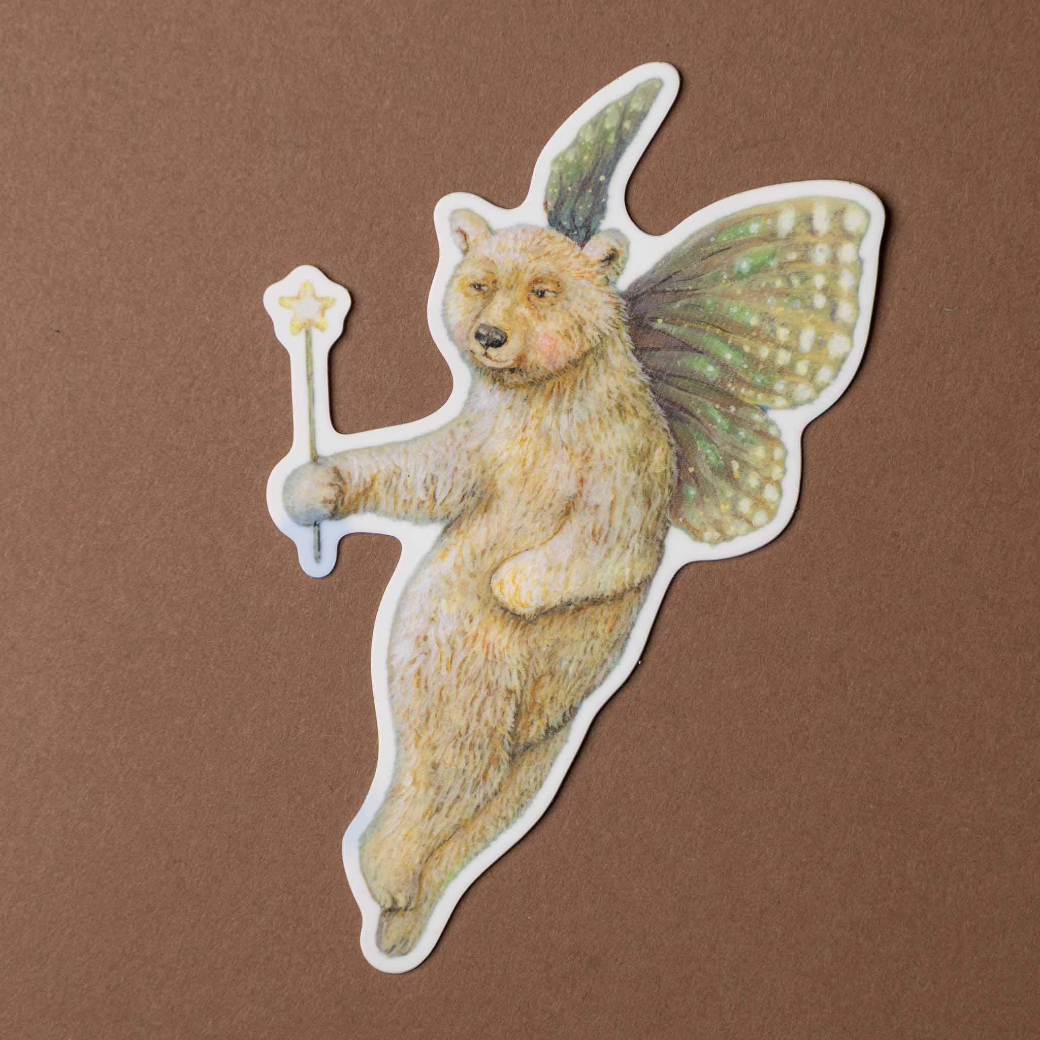 vinyl-die-cut-sticker-faerie-bear Fairy bear sticker with wings and a wand on a brown background