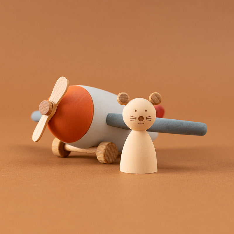 A wooden toy airplane with a mouse figure flying it,