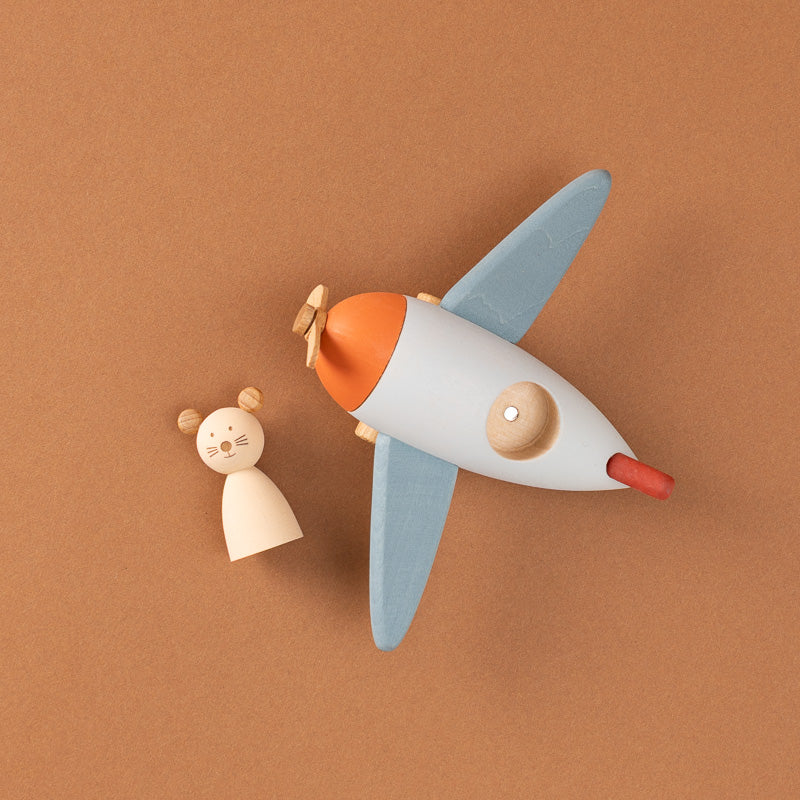 A wooden toy airplane with a mouse figure flying it,