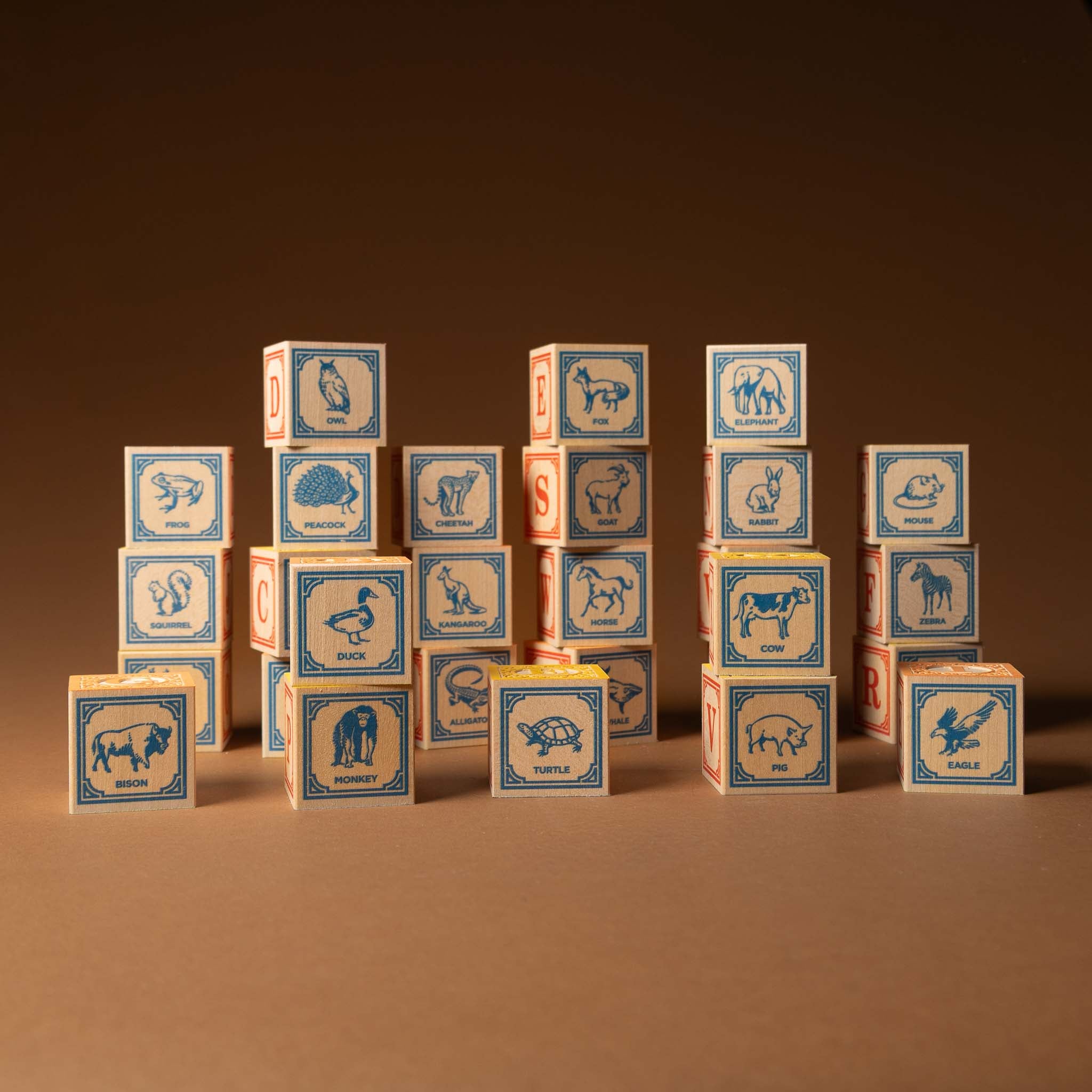 wooden-block-set-with-canvas-bag-classic-abcs Stack of wooden blocks with animal illustrations on a brown background