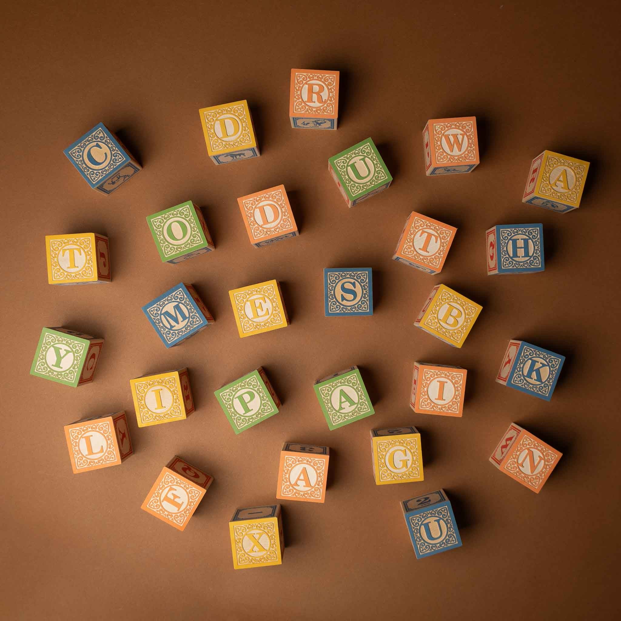 wooden-block-set-with-canvas-bag-classic-abcs Colorful wooden blocks with letters arranged on a brown background
