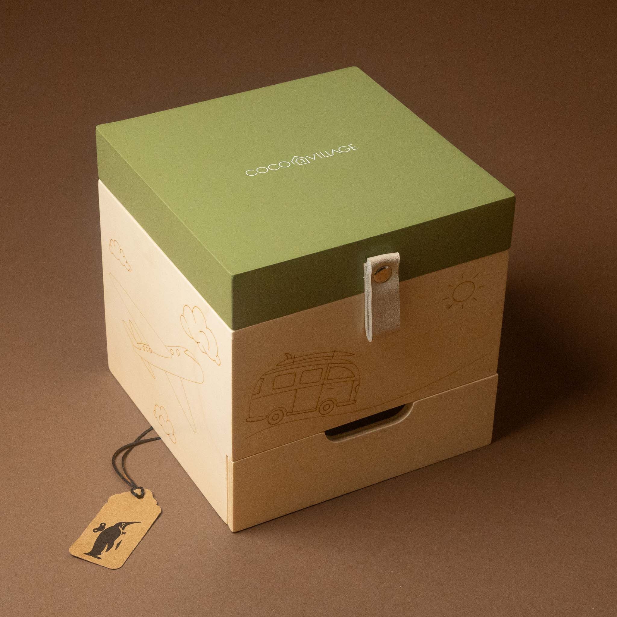 wooden-musical-treasures-box-road-warrier with a muted sage green lid and a natural beige wood-grain drawer base, featuring embossed travel illustrations and a white strap closure. 