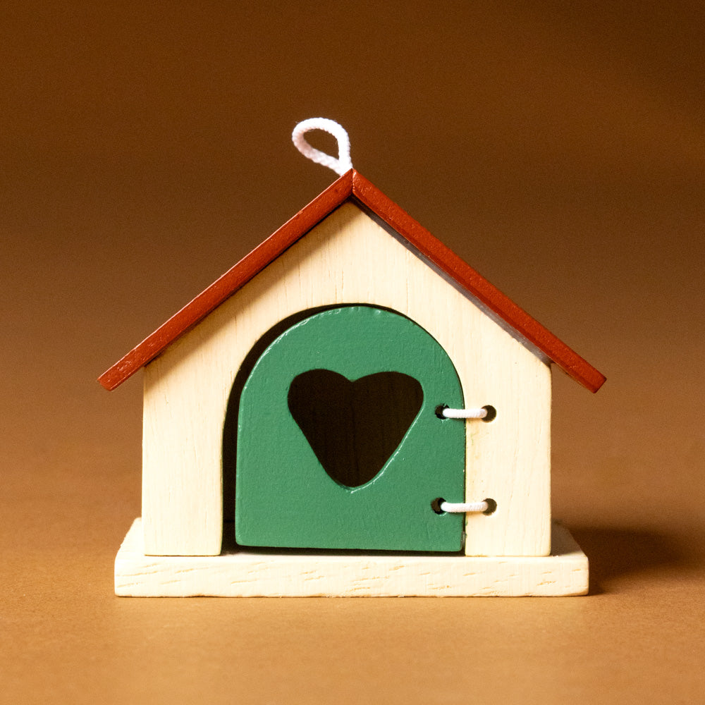 wooden-pet-play-set-dog Small wooden dog house-shaped ornament with a green door and heart cutout on a brown background