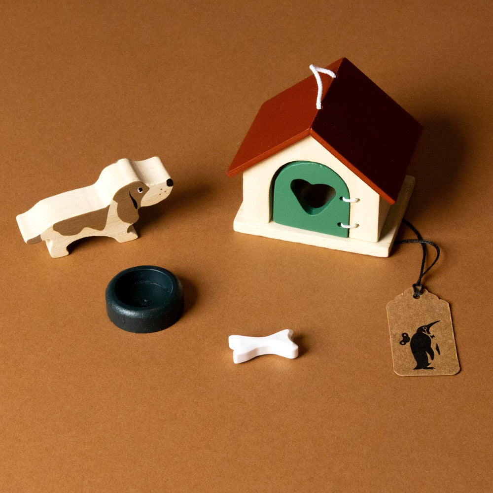 wooden-pet-play-set-dog Miniature dog house with a heart door, dog bone, bowl, and tag on a brown background