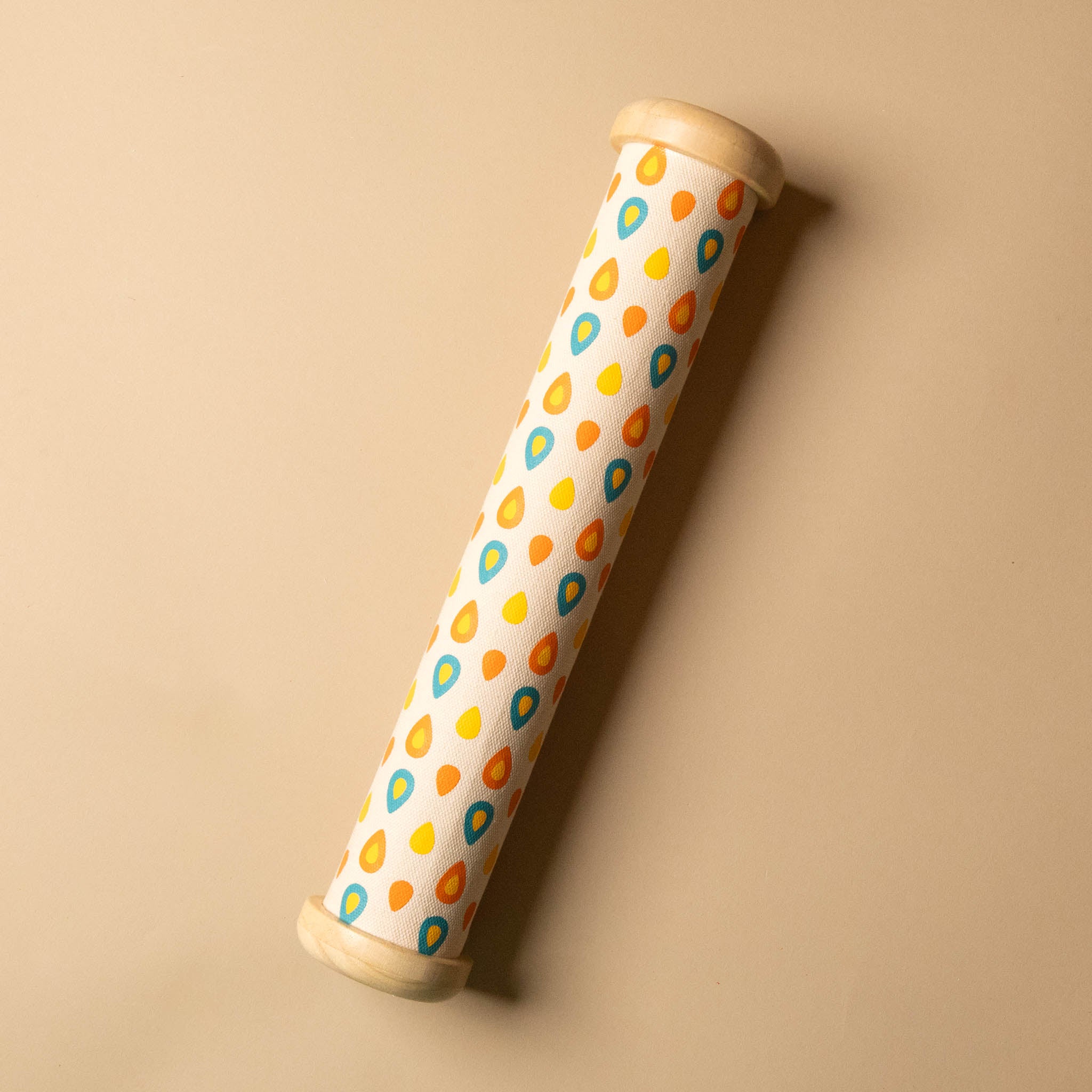 Cylindrical wooden-rainmaker-stick with a patterned design on a beige background