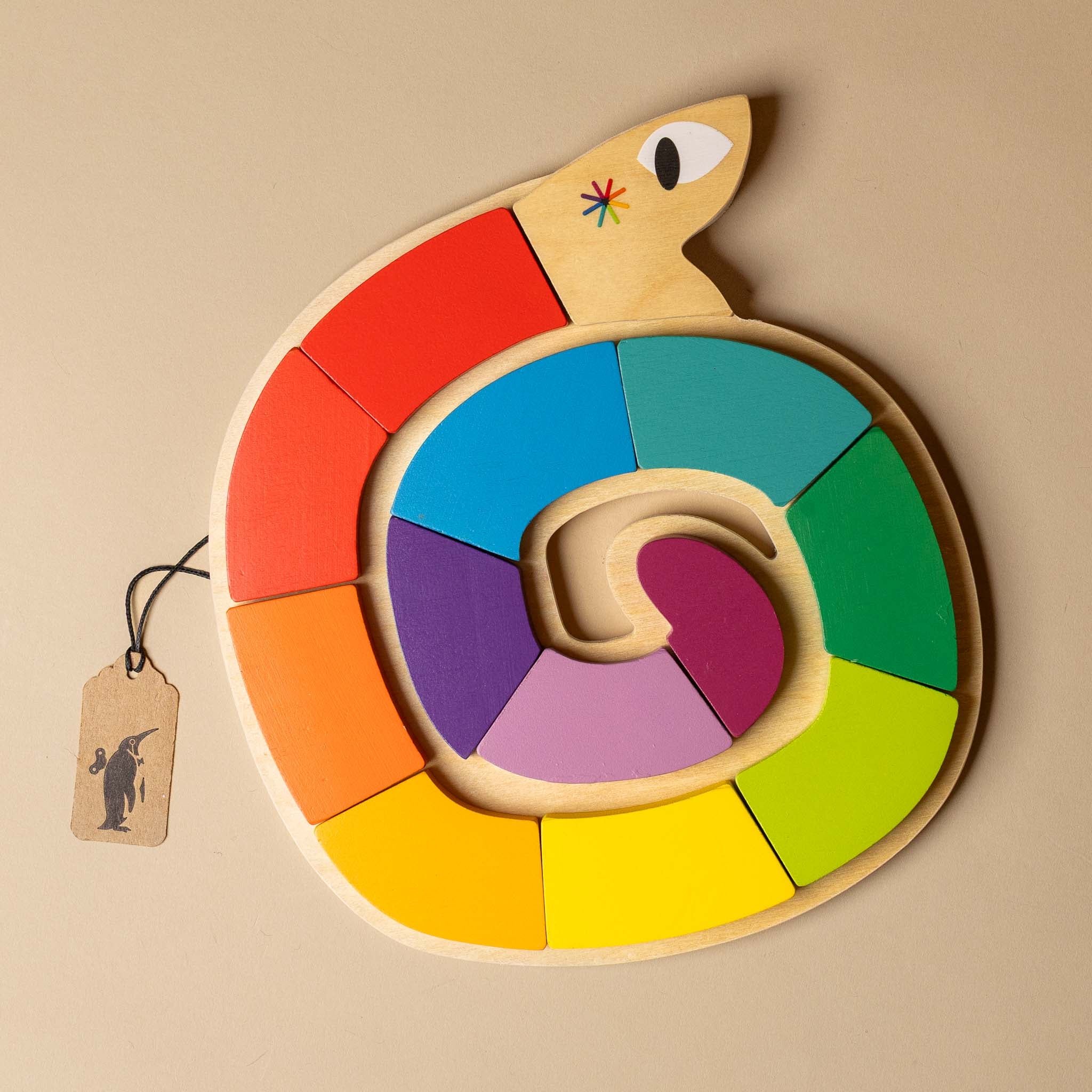 wooden-snake-by-color-puzzle Colorful snake-shaped puzzle toy with wooden body and colorful segments on a beige background.