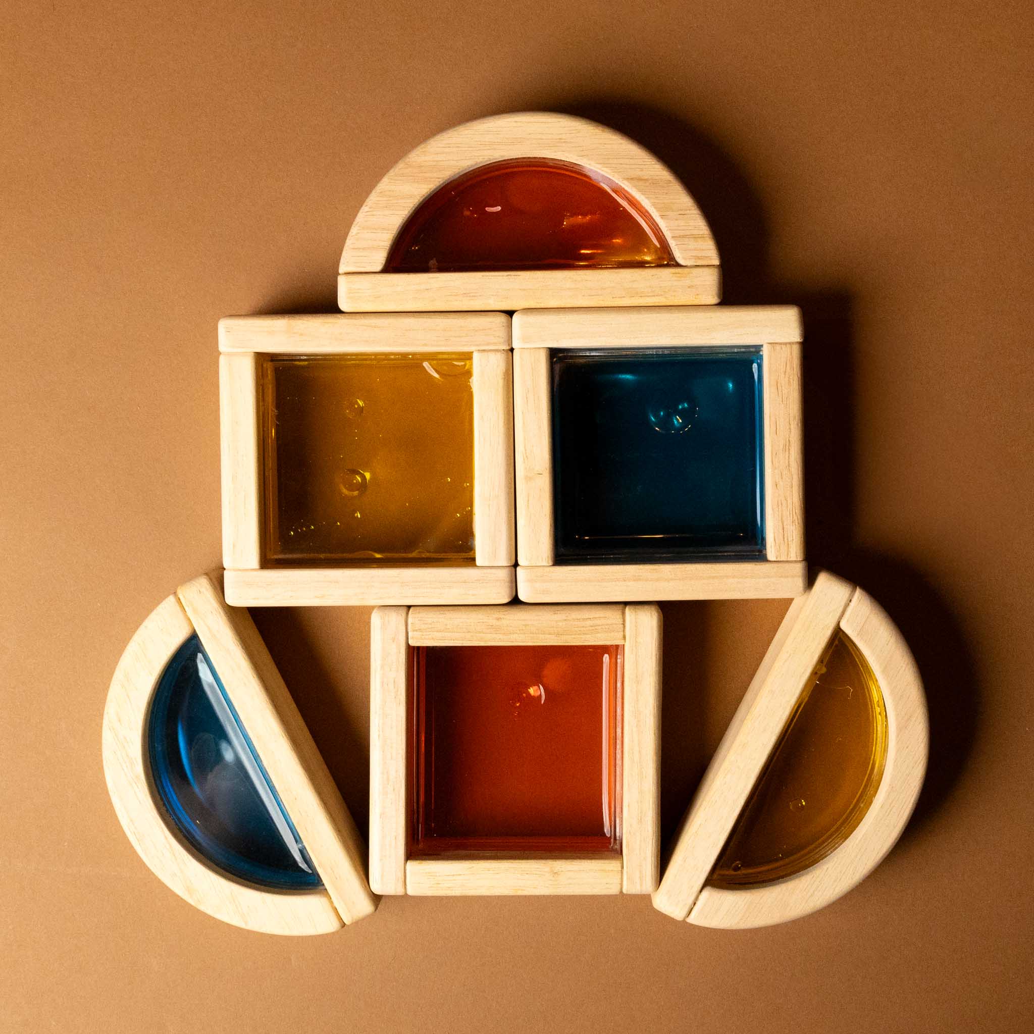 Stack of wooden geometric shapes with colored liquids on a brown background
