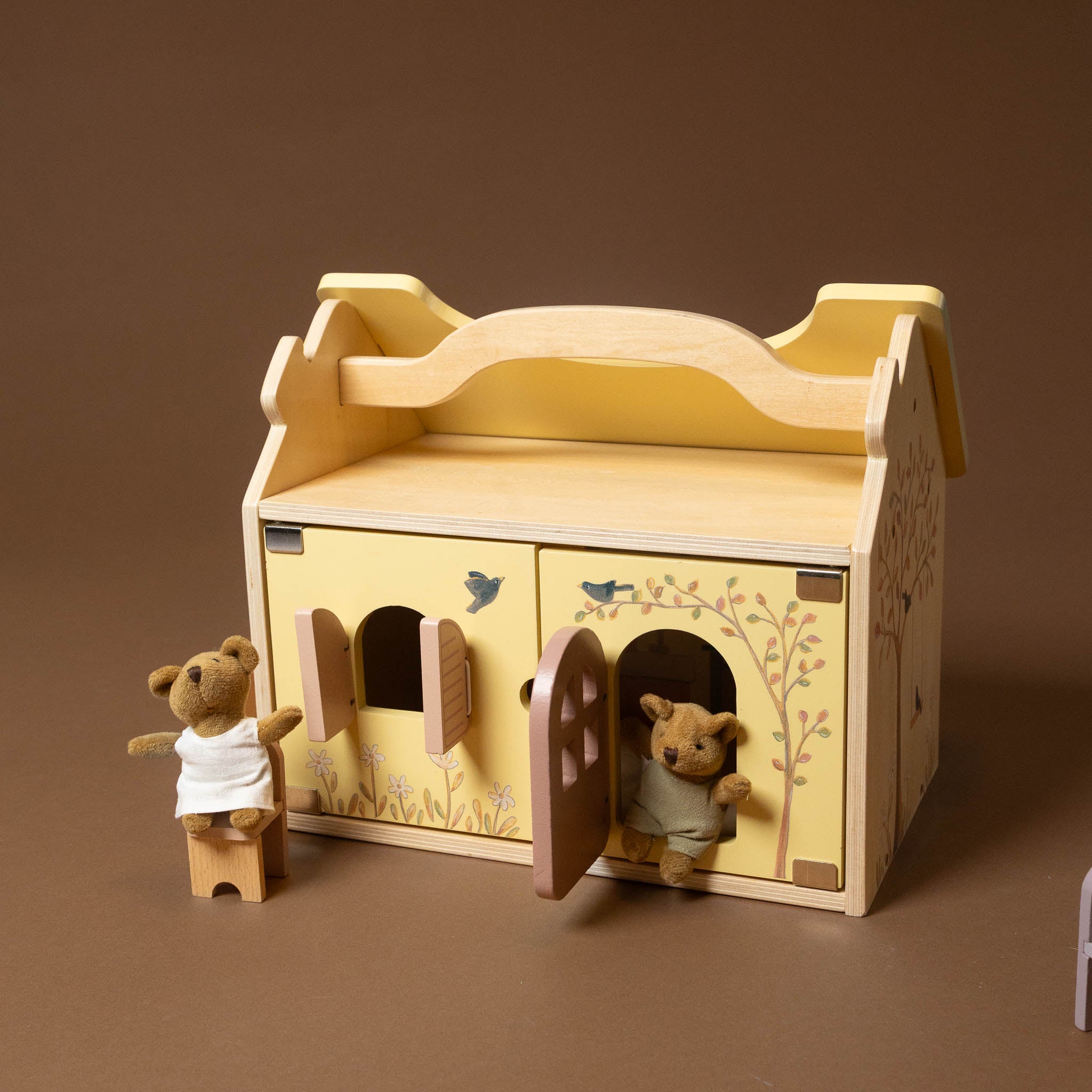 Wooden toy house with two teddy bears on a brown background