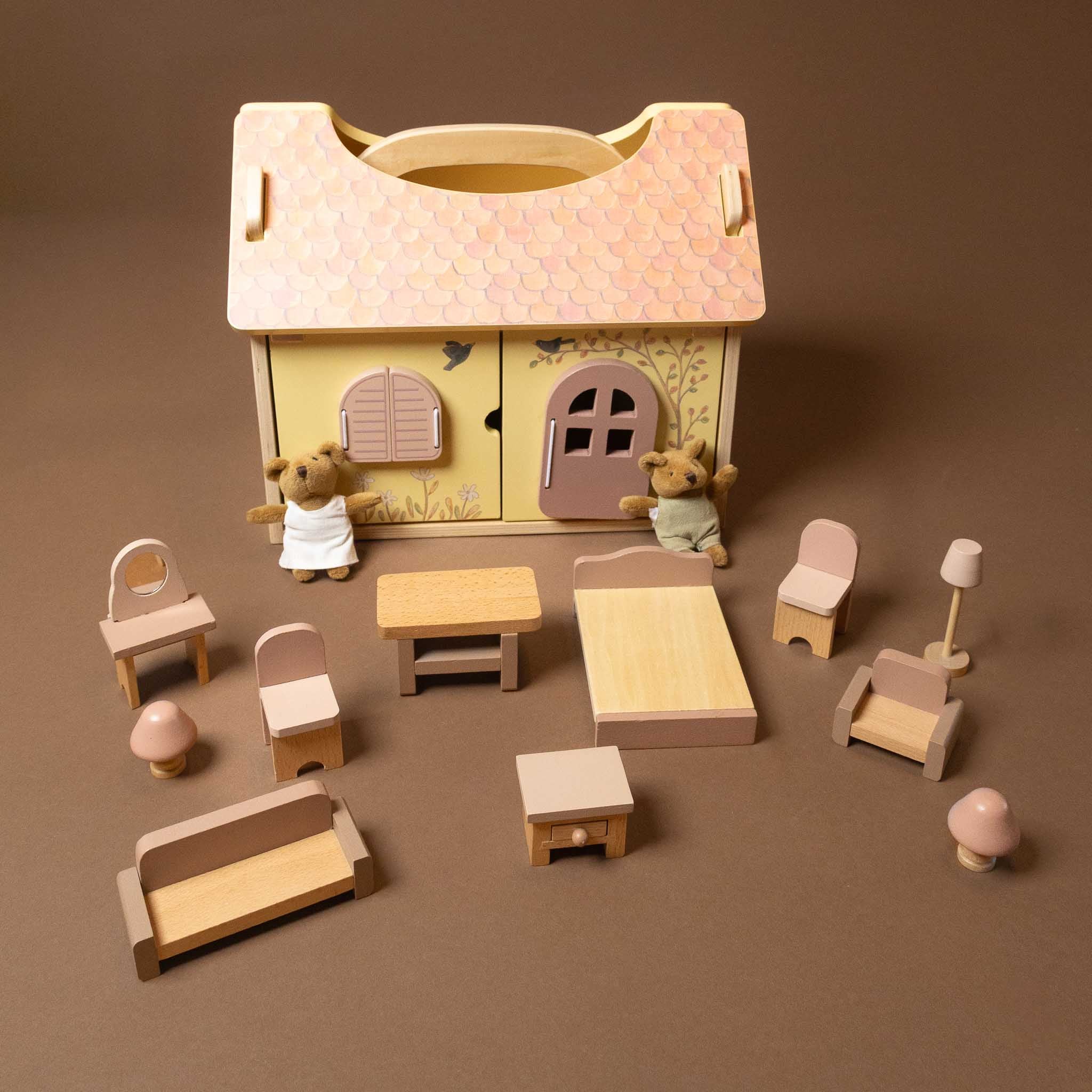 Wooden toy house with teddy bear characters and furniture on a brown background